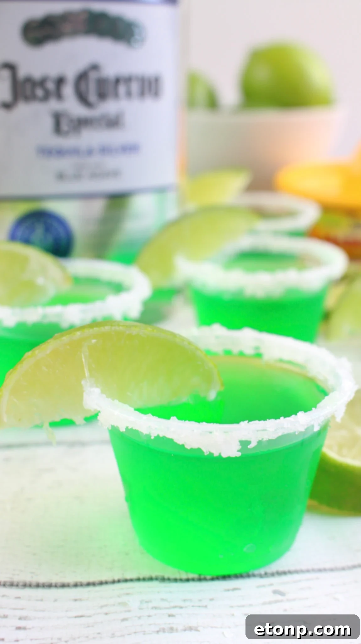 Margarita Jello Shots 4 Margarita Jello Shots lined up on a serving tray, some with salt rims and others with sugar, offering a personalized touch for guests.