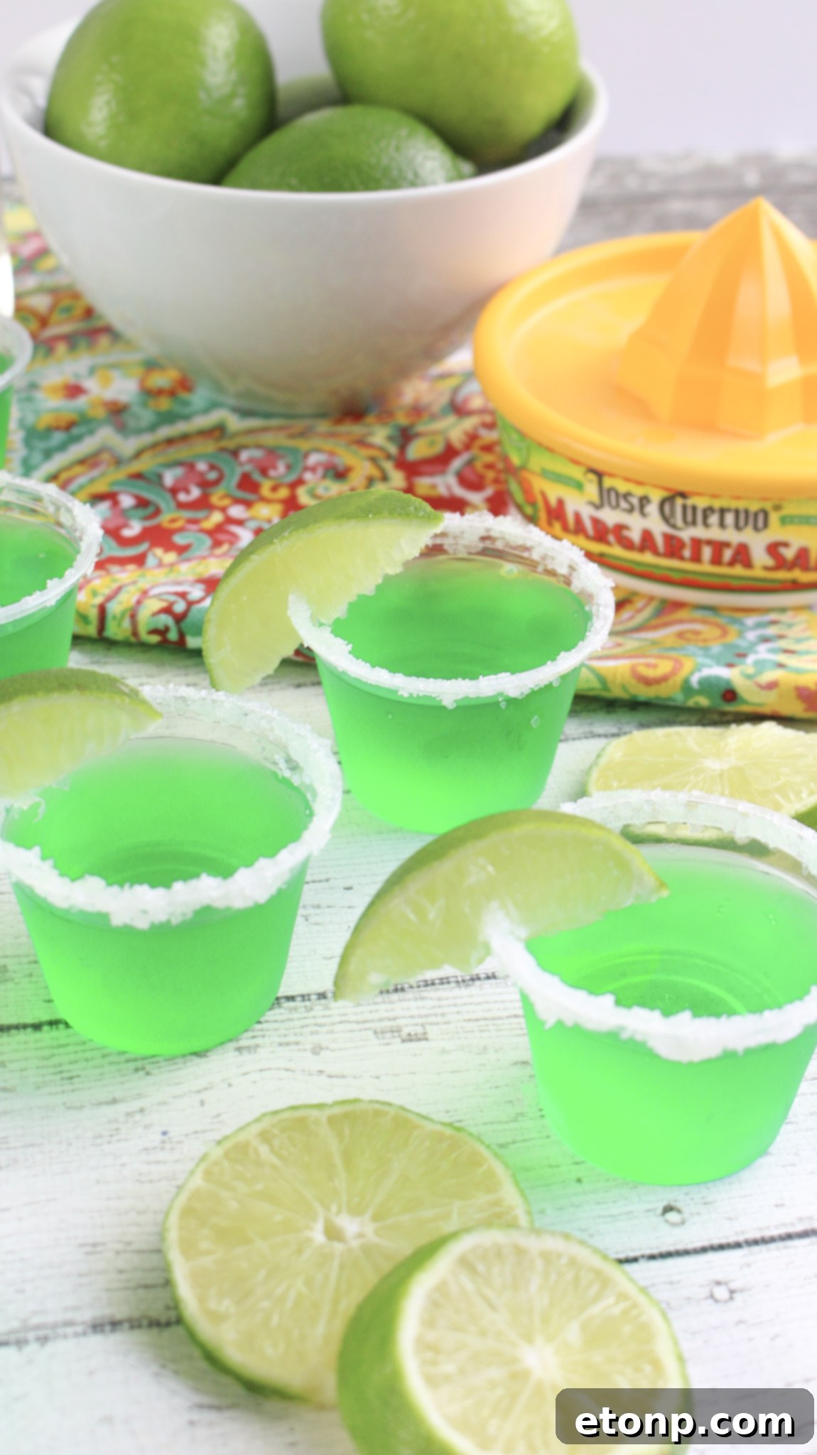 Margarita Jello Shots 8 A hand reaching for a Margarita Jello Shot from a group arranged on a festive backdrop, emphasizing their popularity and quick disappearance.