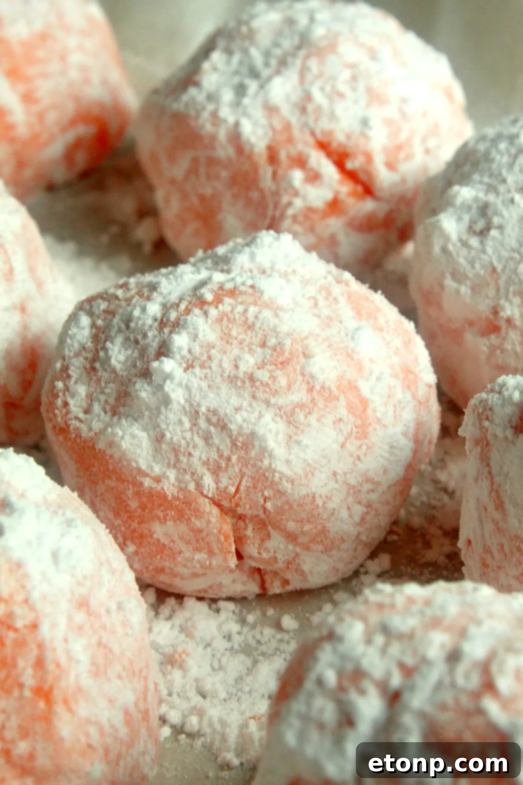 Close-up of a single Orange Creamsicle Truffle, showing its smooth texture and dusting of confectioners sugar
