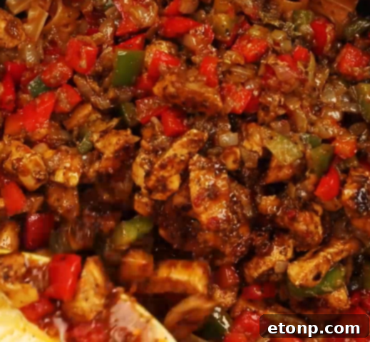 Colorful bell peppers and onions sautéing in a skillet, a key component of fajita pasta