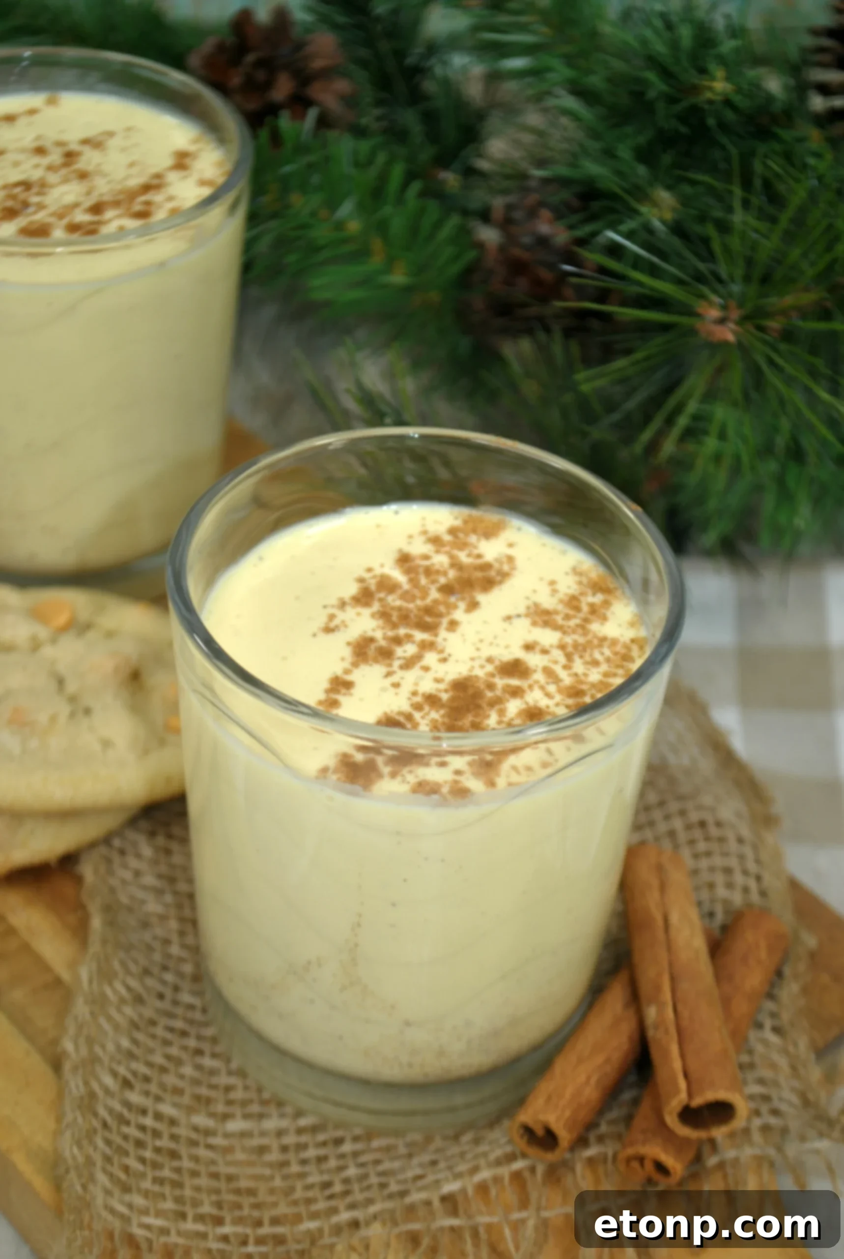 Classic Homemade Eggnog 4 Several clear glass bottles and elegant glasses filled with creamy homemade eggnog, positioned on a light background, suggesting readiness for chilling and serving.