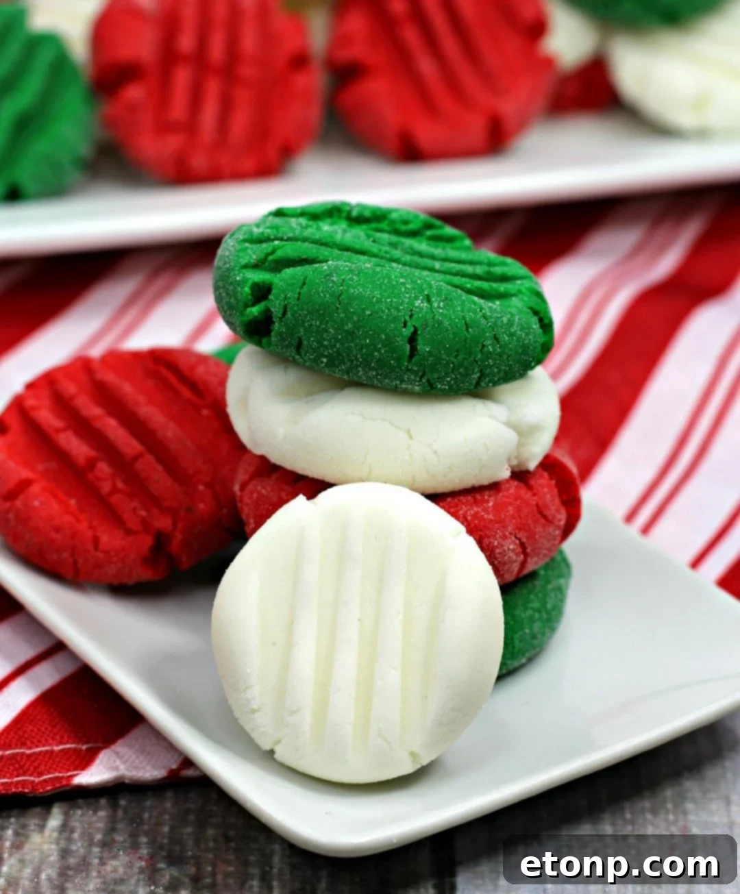 Close-up of vibrant red, green, and white peppermint patties dusted with sugar, arranged festively.