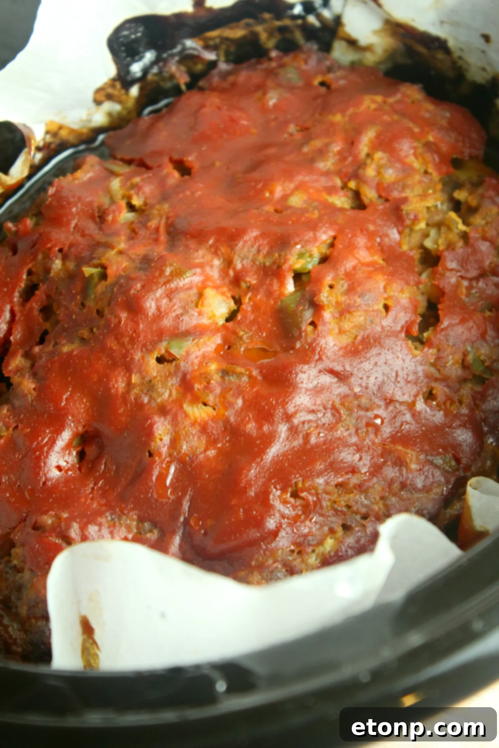 Close-up of a slice of moist slow cooker meatloaf with glaze, ready to enjoy.