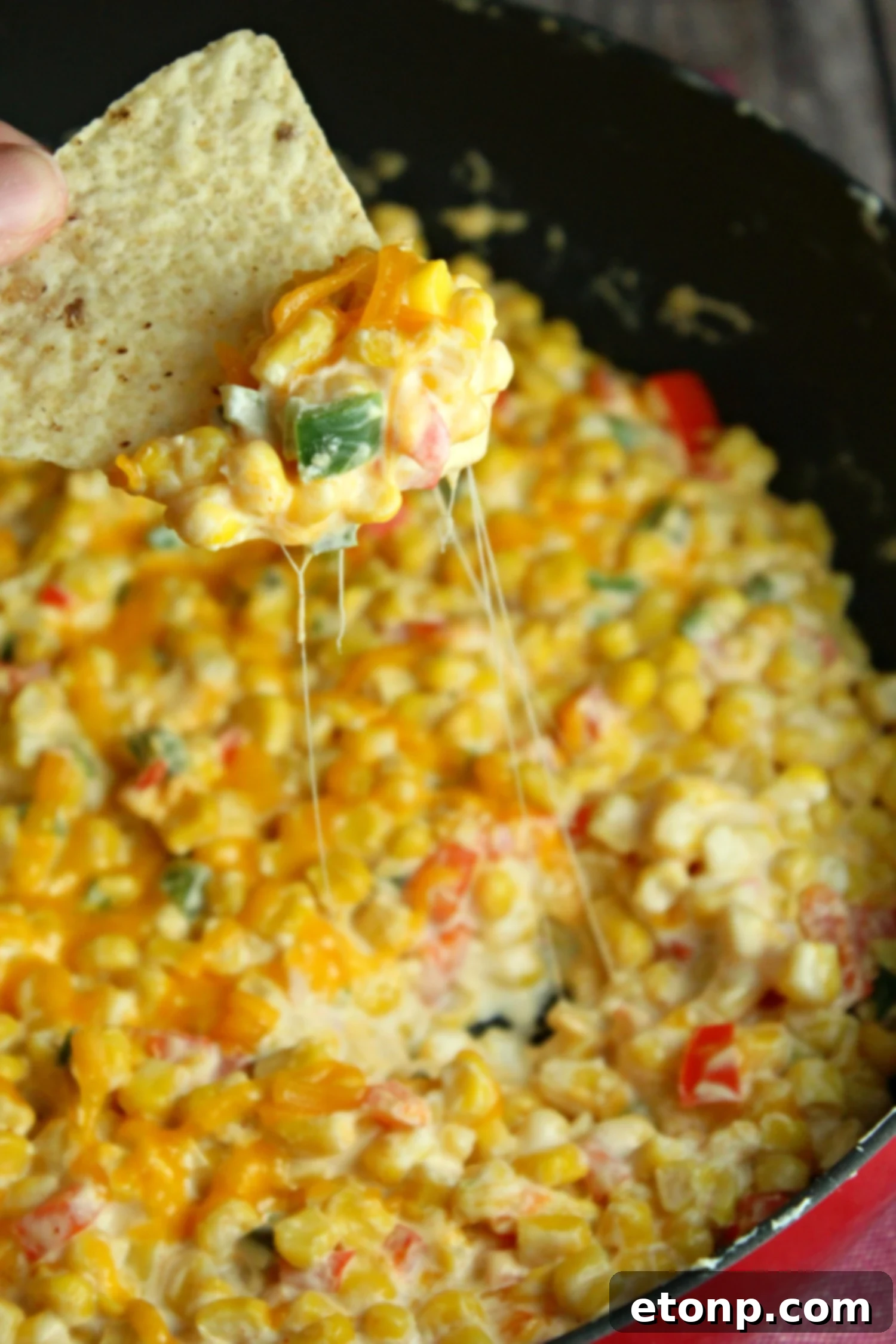 A close-up shot of the finished hot corn dip, showcasing its golden-brown melted cheese topping and creamy interior.