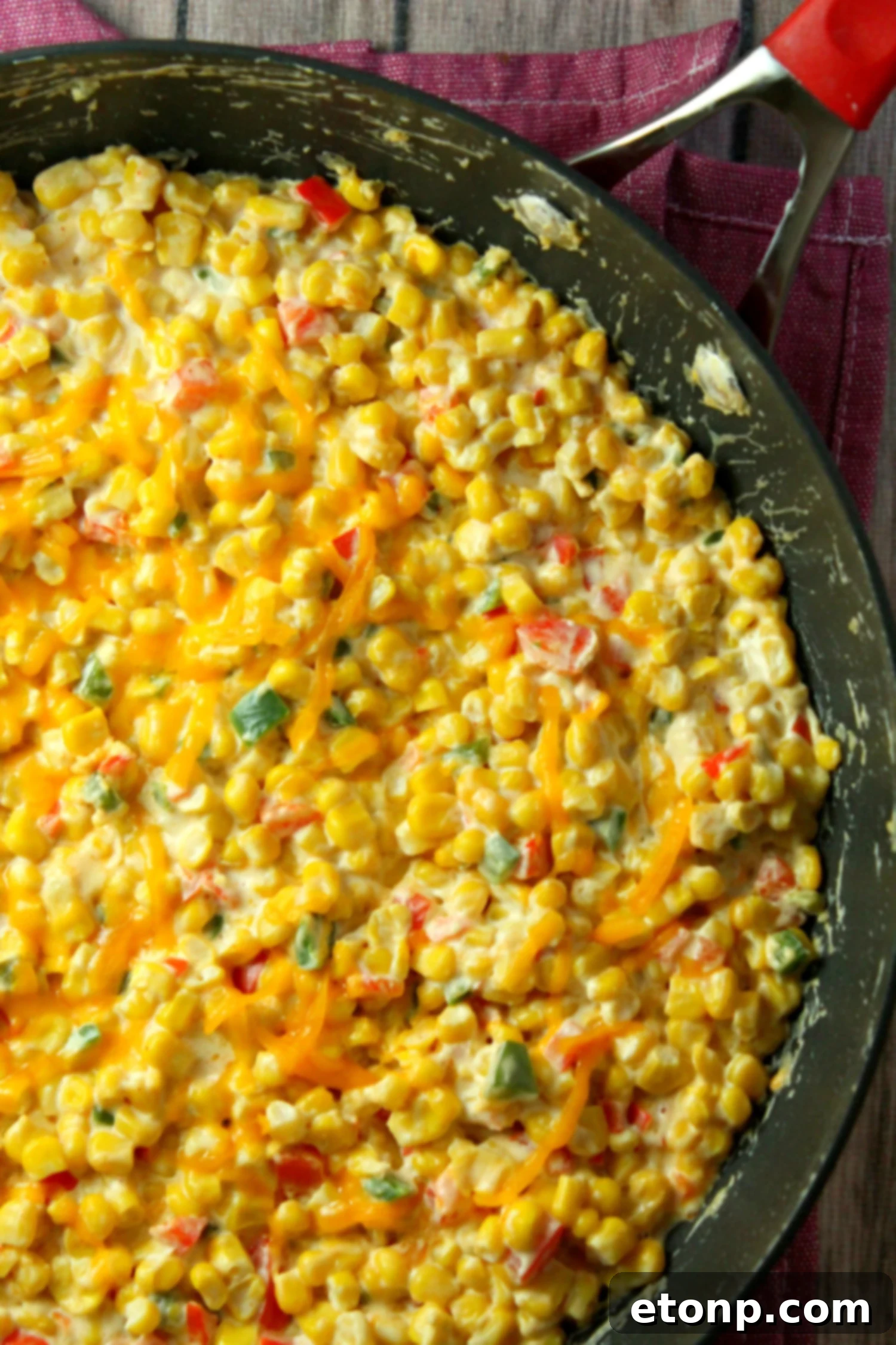 Ingredients for the hot corn dip laid out on a cutting board, including corn, jalapeños, bell peppers, and cheese.