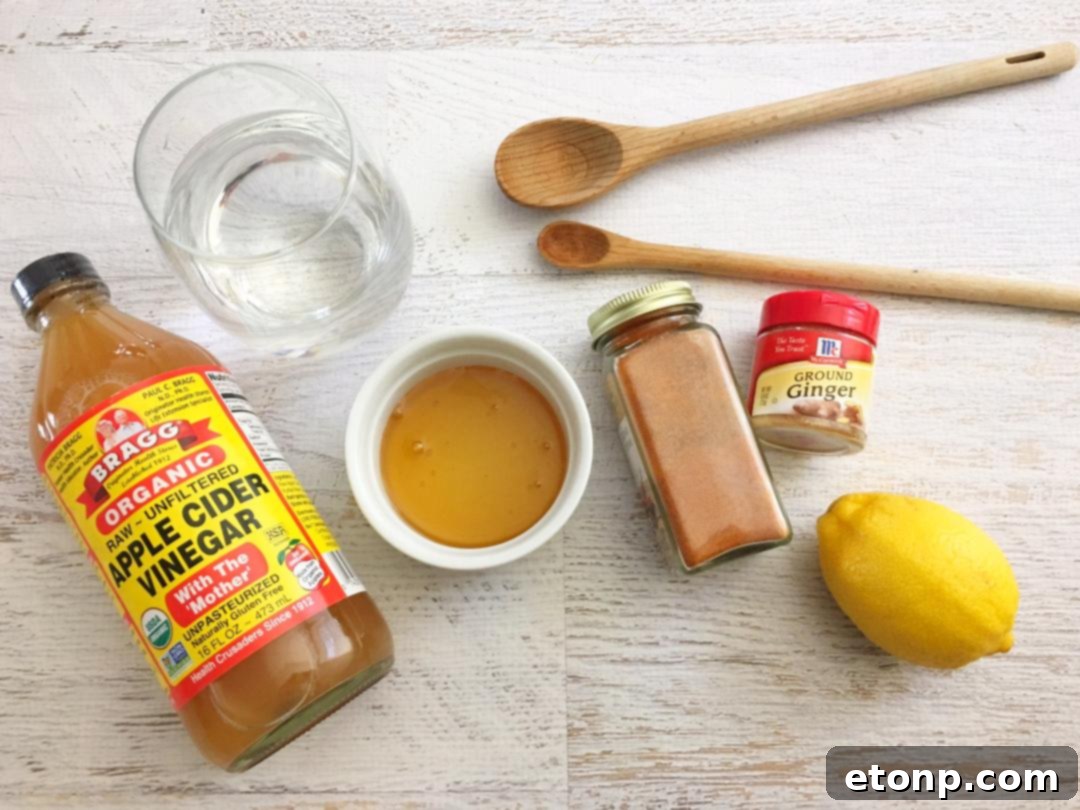 An array of fresh, natural ingredients for homemade cough syrup, including Bragg's apple cider vinegar, honey, lemons, and ginger, neatly arranged on a rustic wooden surface.