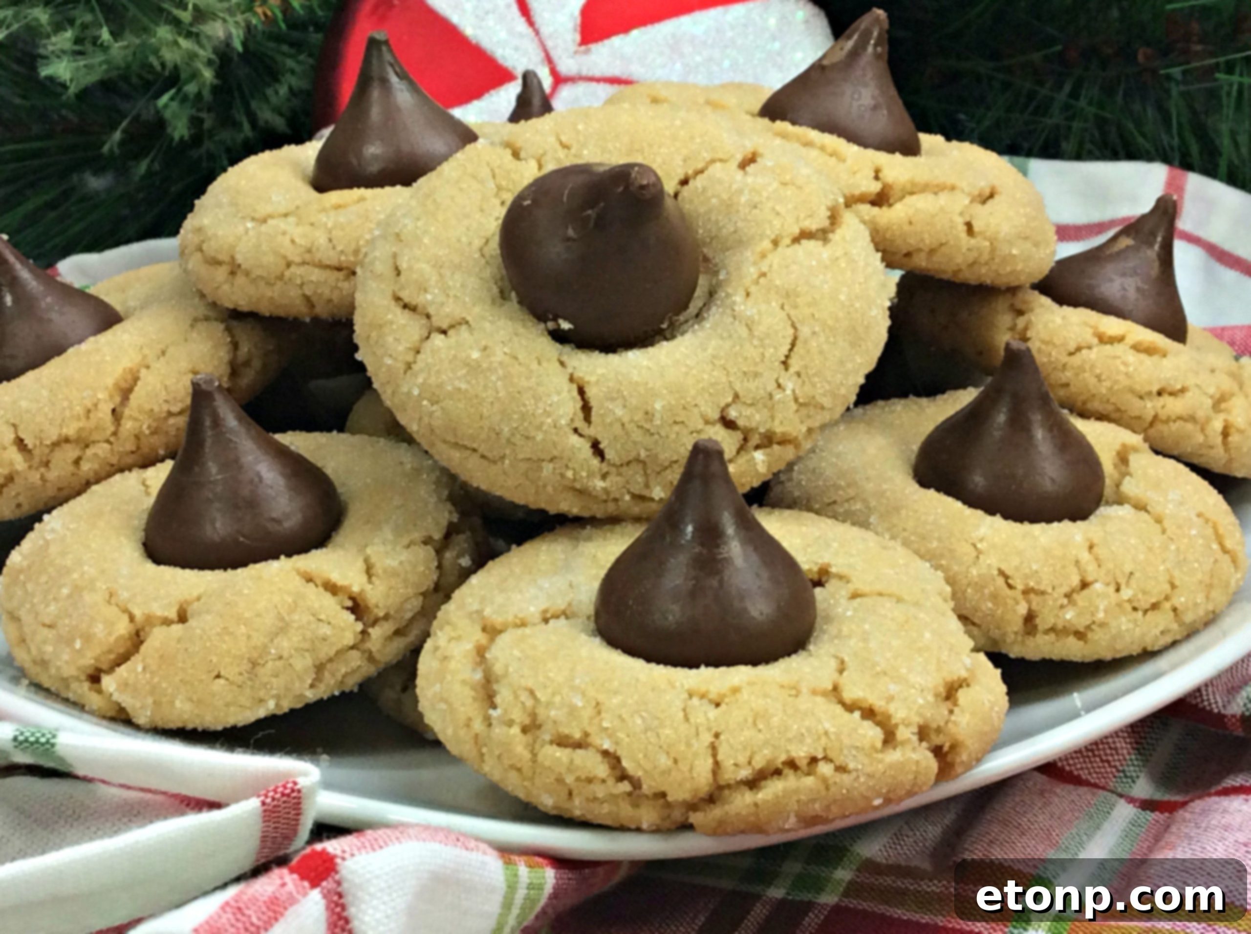 A plate full of golden brown Peanut Butter Blossom Cookies, each with a slightly indented Hershey's Kiss, showcasing their classic appeal.