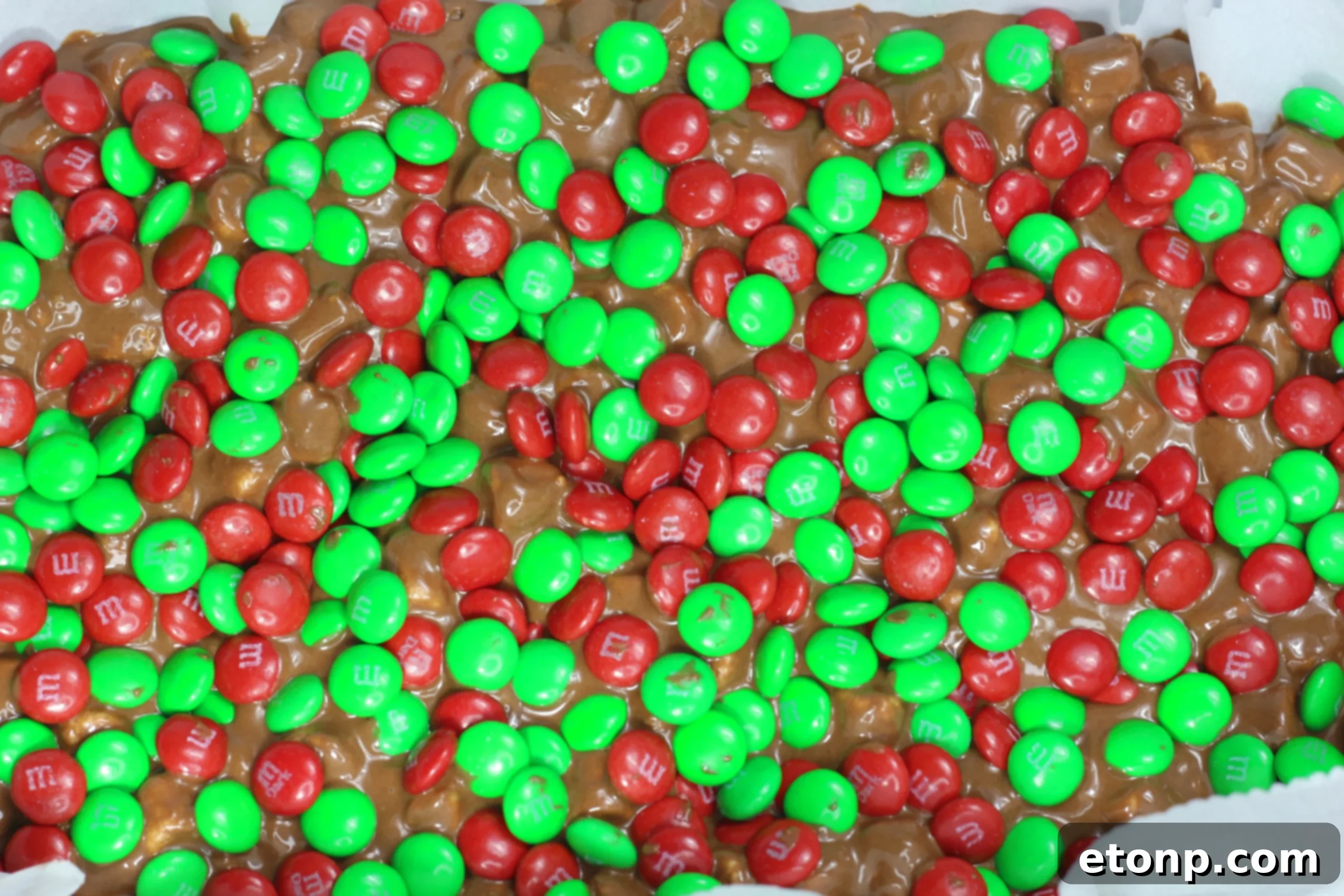 No-bake marshmallow mixture topped with colorful red and green M&M's, ready for chilling.