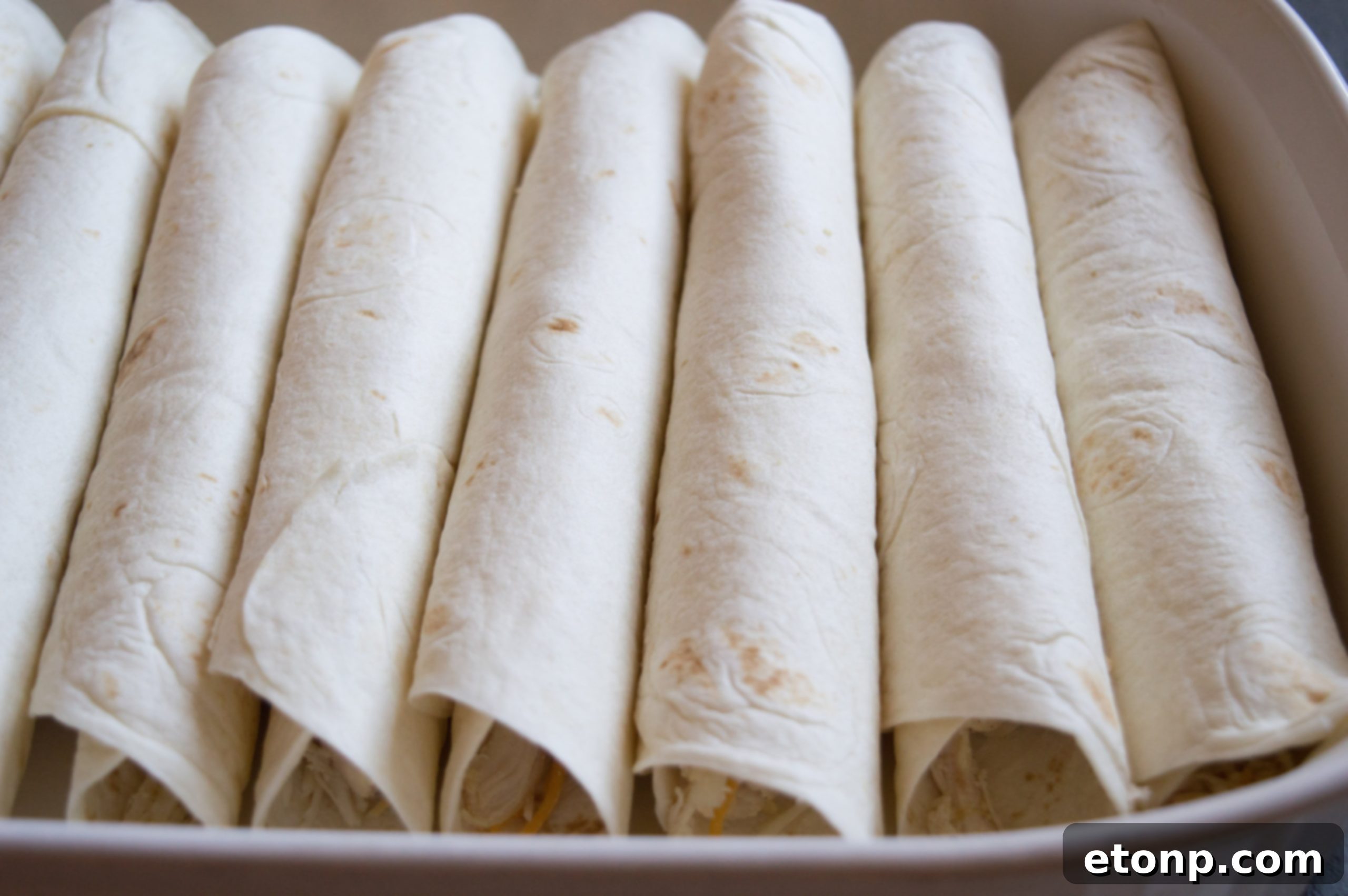 Close-up of bubbling white chicken enchiladas with a golden-brown, melted cheese topping