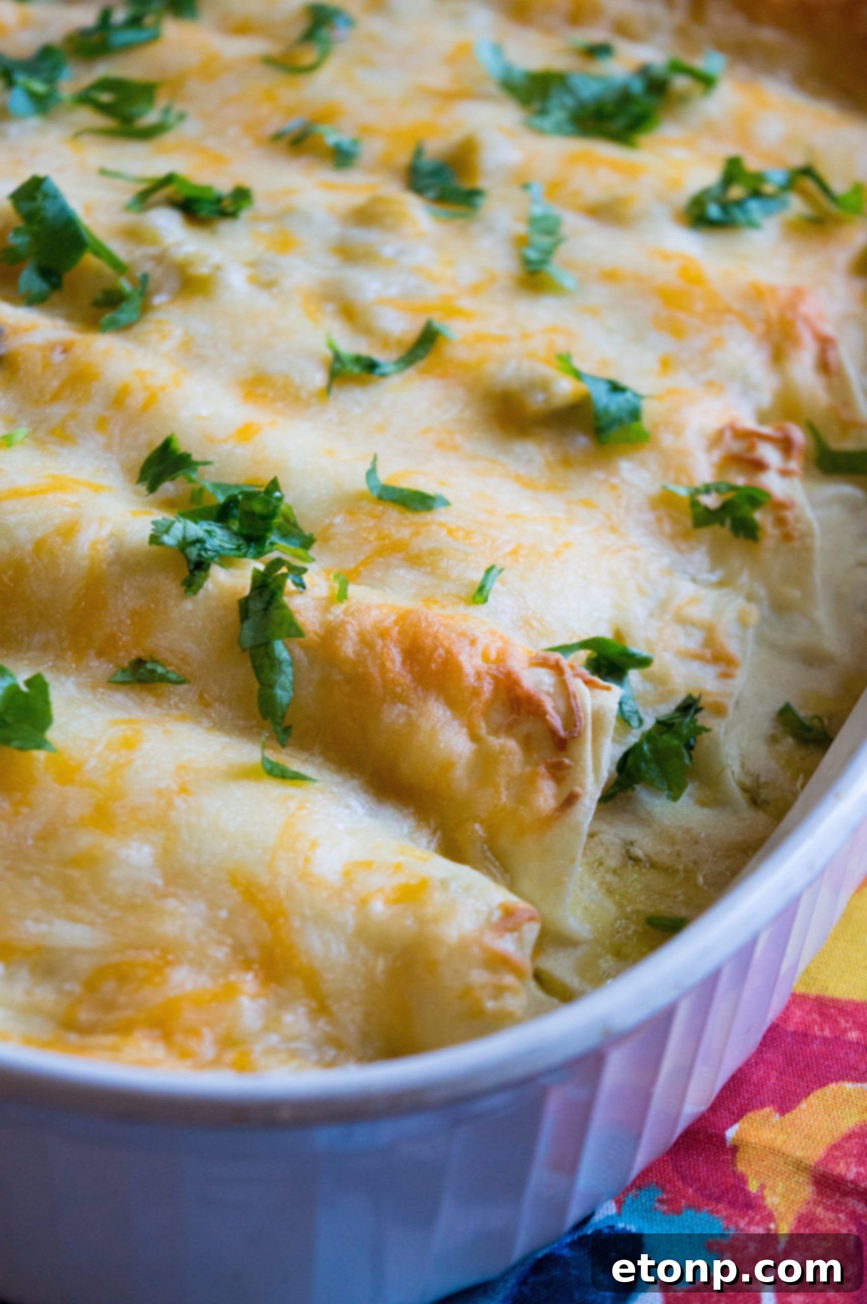 Close-up of a single White Chicken Enchilada being carefully lifted from the casserole dish, revealing its creamy interior