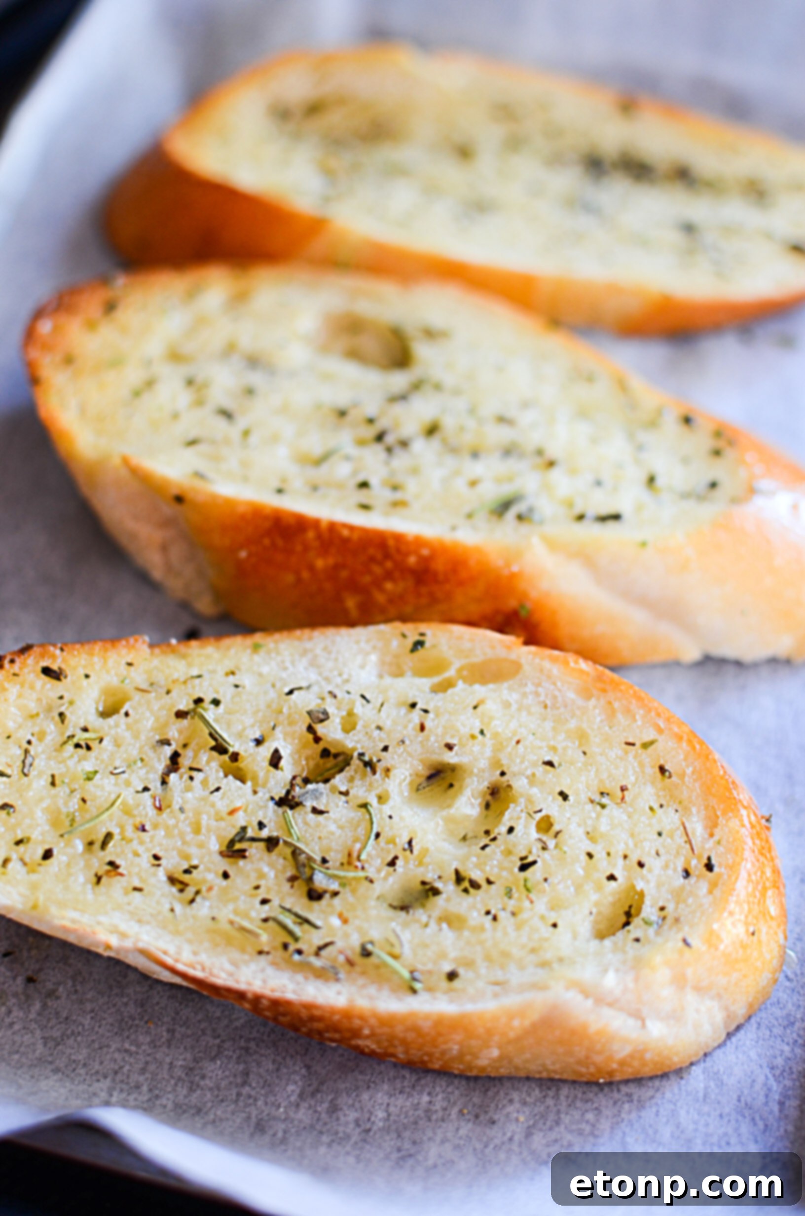 Close-up of garlic parmesan bread, showing melted cheese and herbs.
