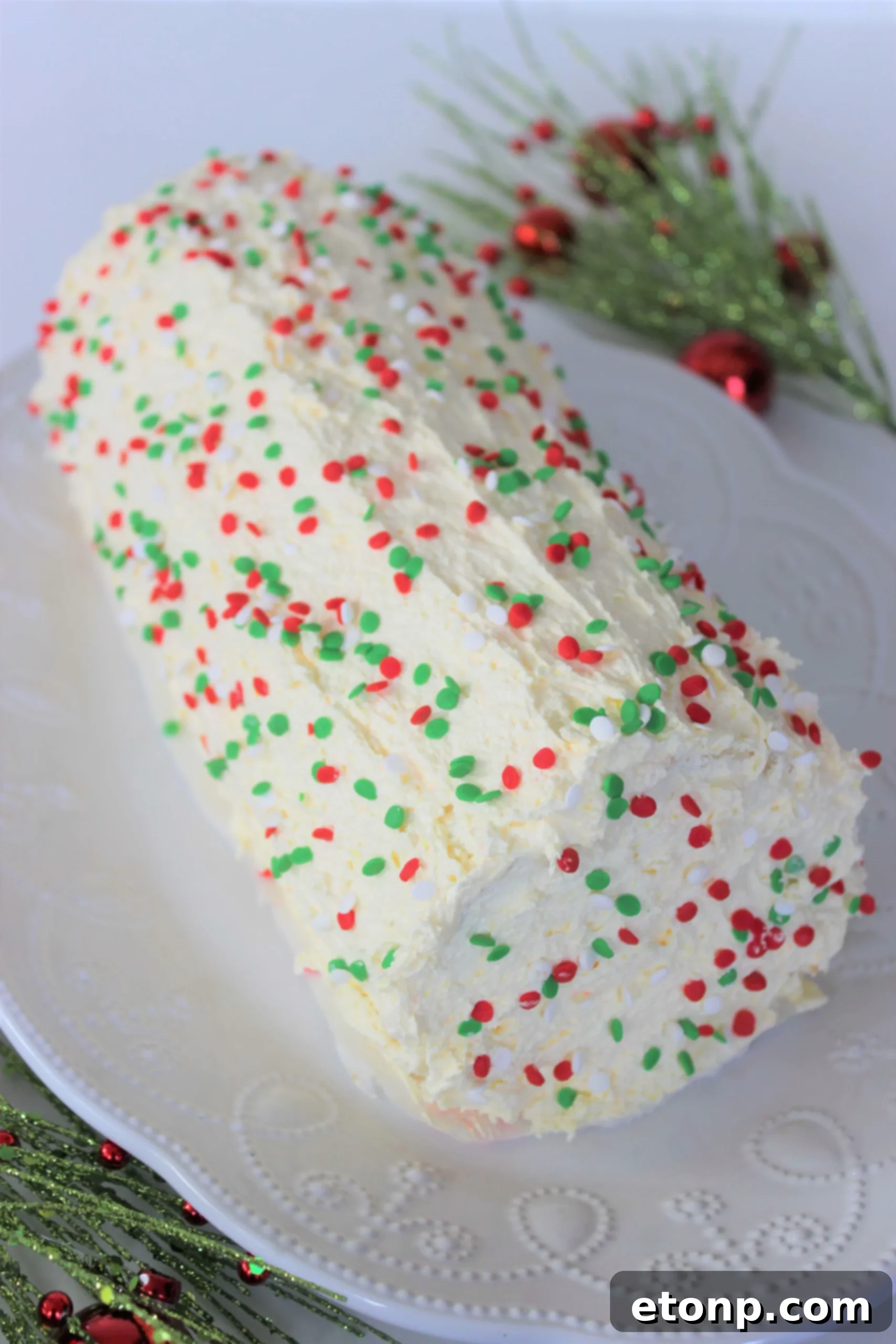 Christmas Cake Roll Made Easy 2 Beautifully decorated Christmas Cake Roll, sliced to show the festive red and white swirl inside.
