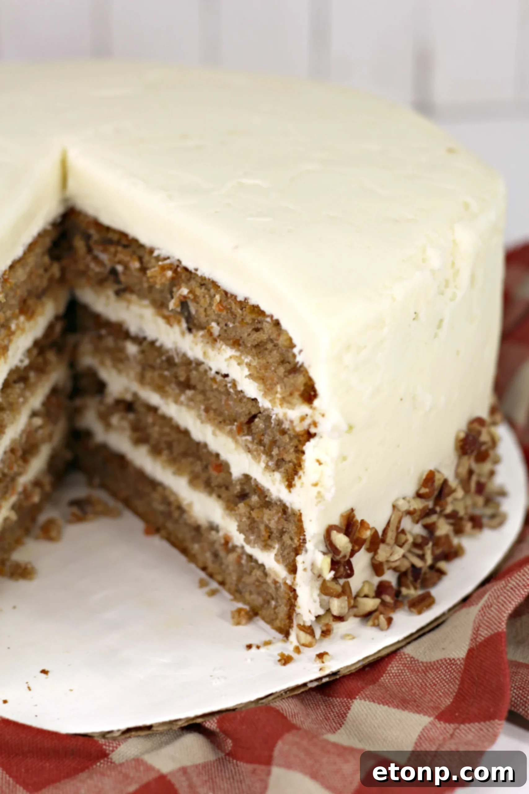 Beautifully frosted carrot cake, showing its layers and pecan garnish.