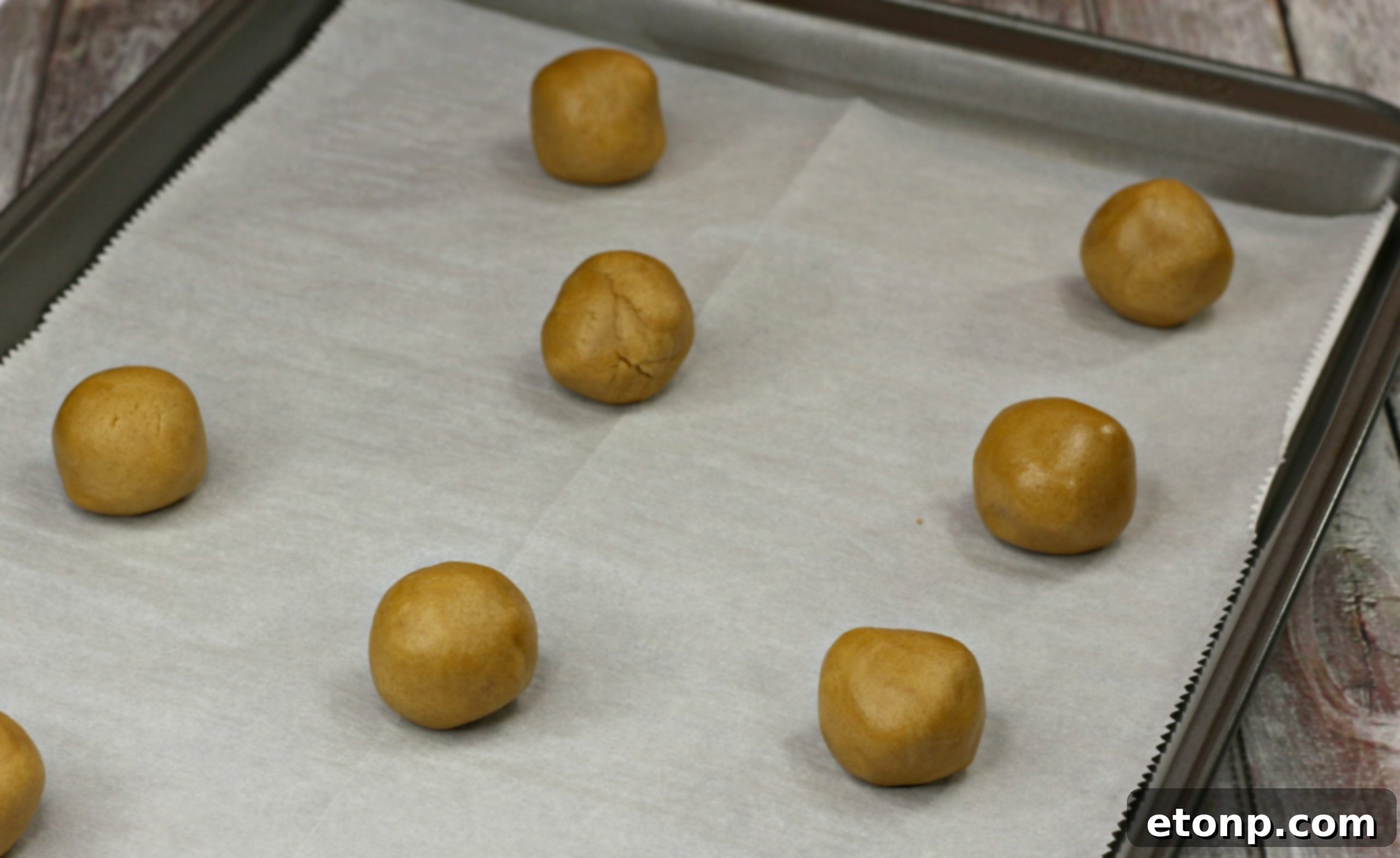 Close-up of perfectly shaped Nutterbutter cookie dough balls on a baking sheet before baking.