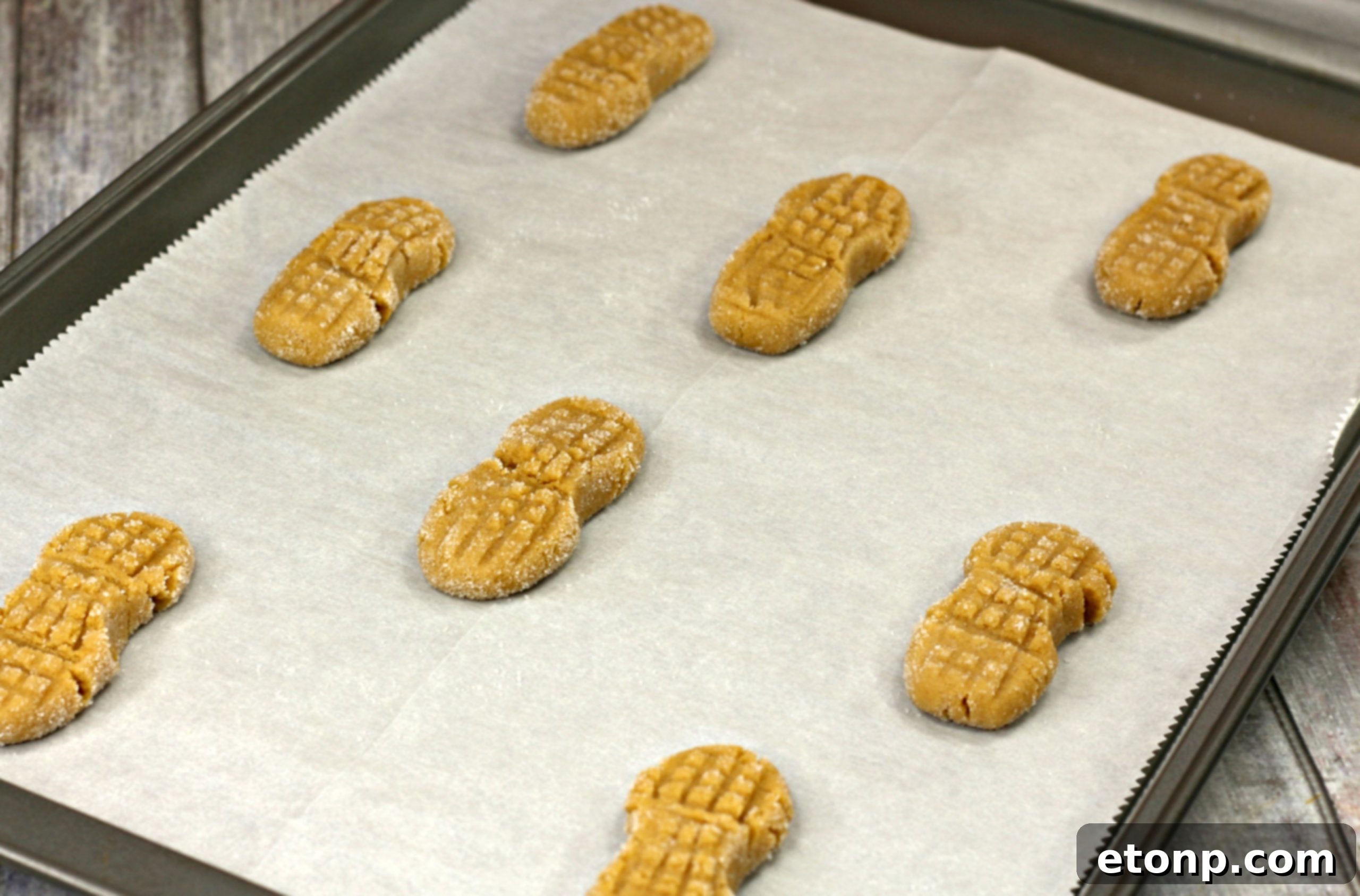 Hands rolling Nutterbutter cookie dough in granulated sugar for a sweet coating.