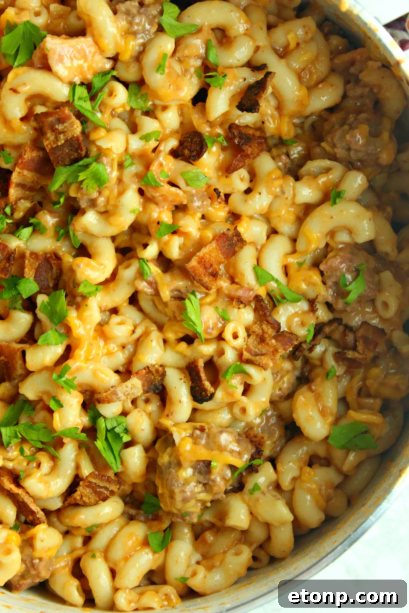 Loaded Ooey Gooey Bacon Cheeseburger Pasta 2 A large skillet filled with creamy, cheesy bacon cheeseburger pasta, garnished with fresh parsley.