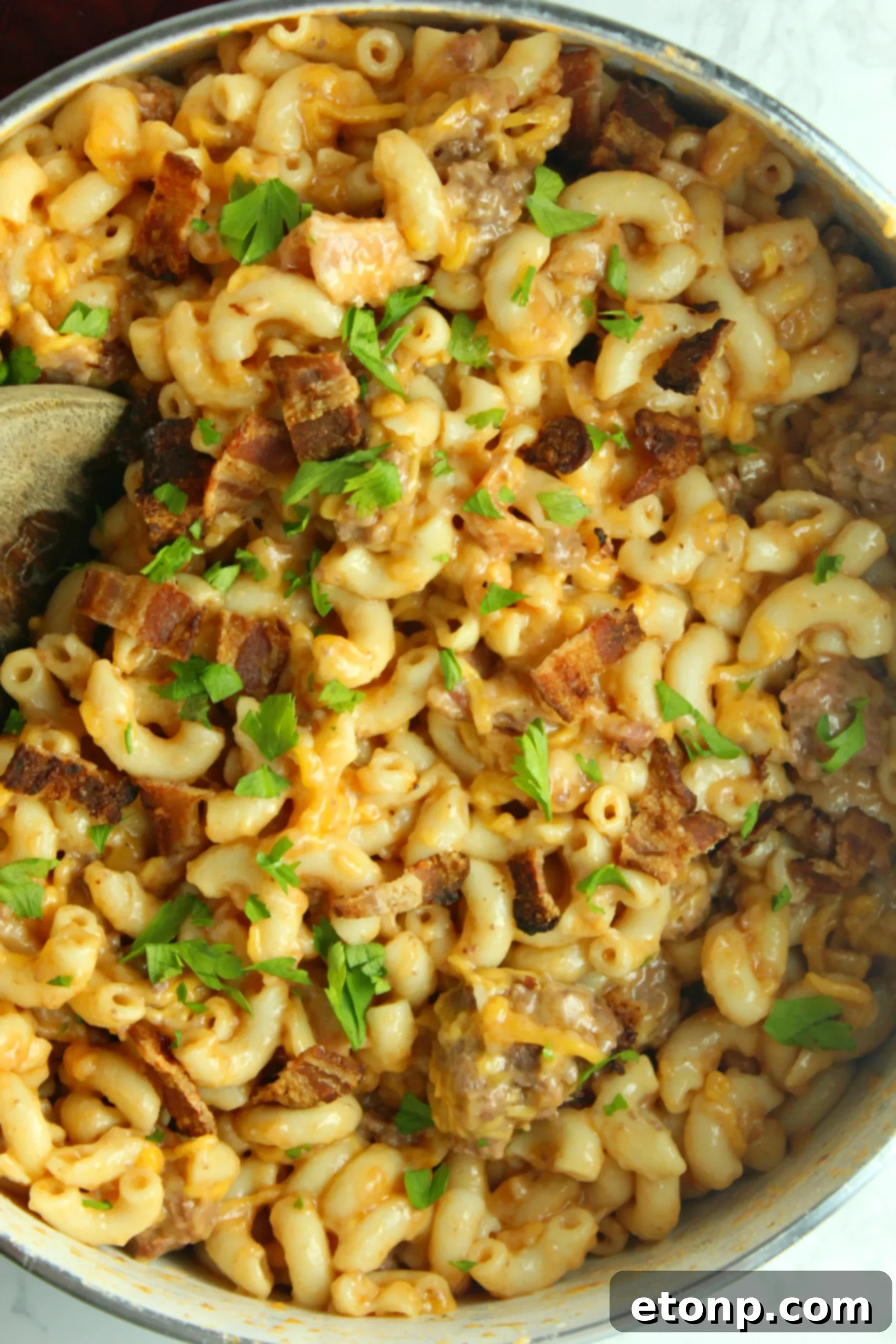 Loaded Ooey Gooey Bacon Cheeseburger Pasta 4 A portion of Bacon Cheeseburger Pasta served in a bowl, with a fresh green side salad in the background.
