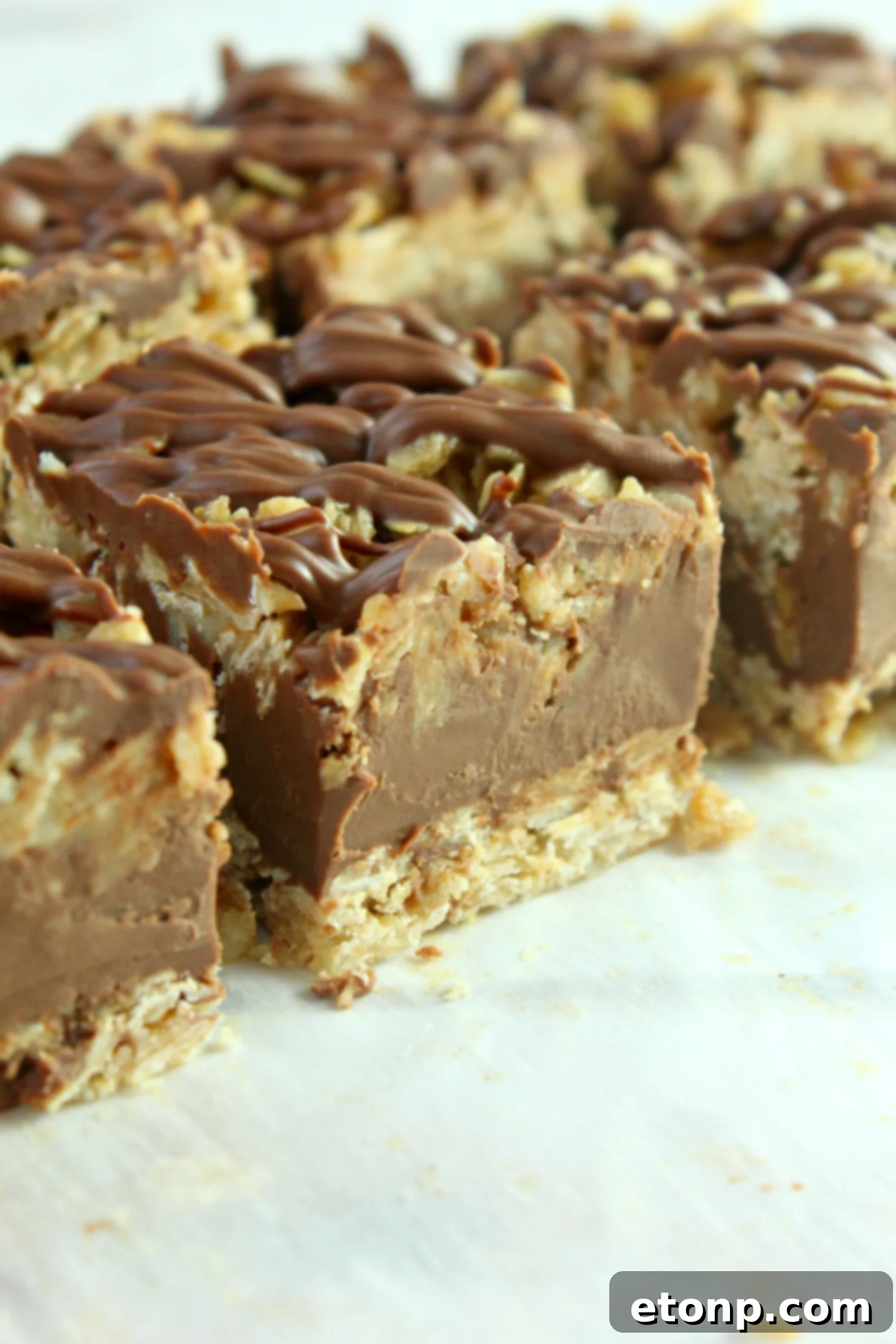 Effortless Chocolate Oatmeal Bliss Bars 6 A hand reaching for a piece of no-bake chocolate oatmeal bar from a pan
