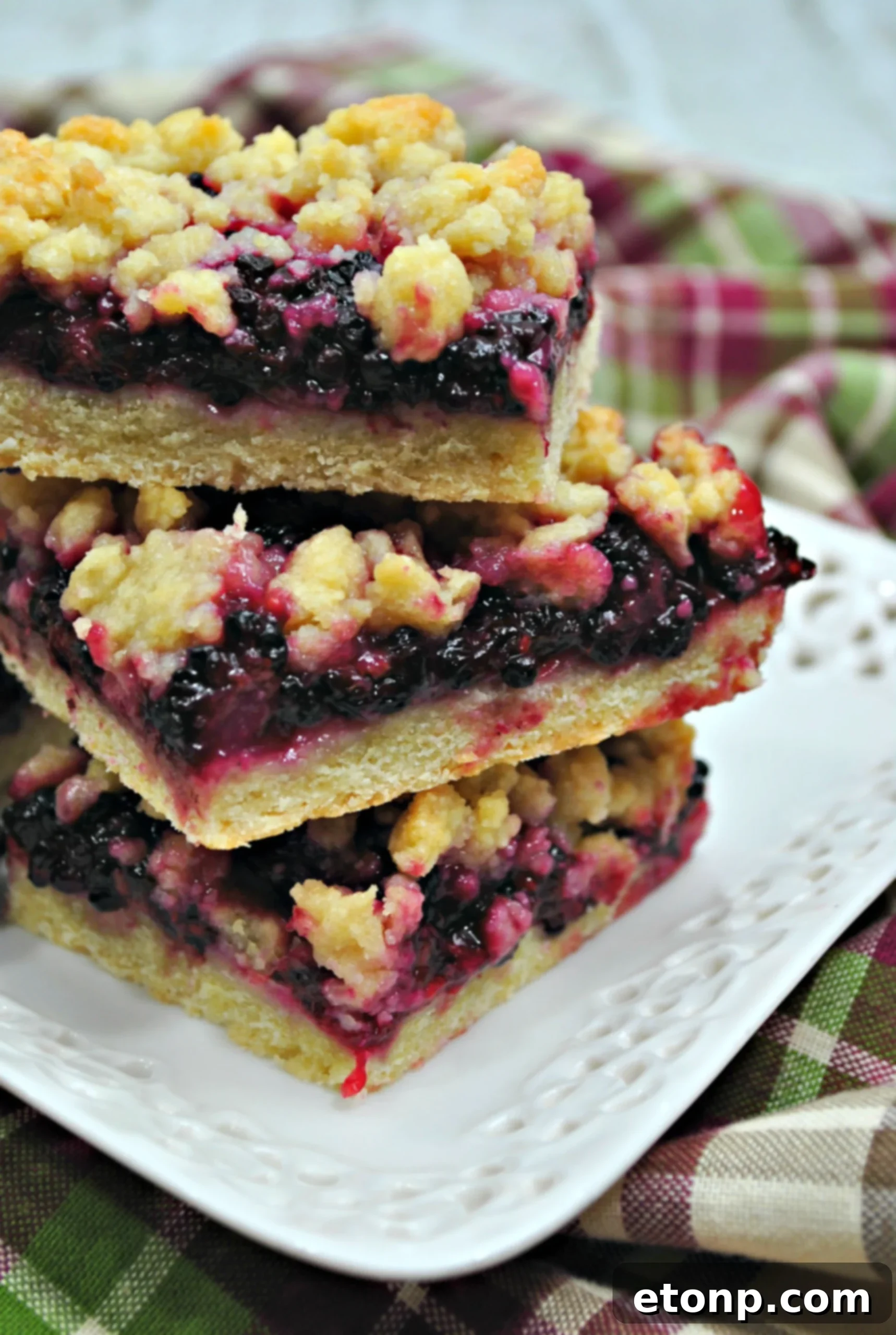 Close-up of a perfectly baked blackberry pie crumble bar, showcasing the golden-brown crumble topping and a hint of purple blackberry filling.