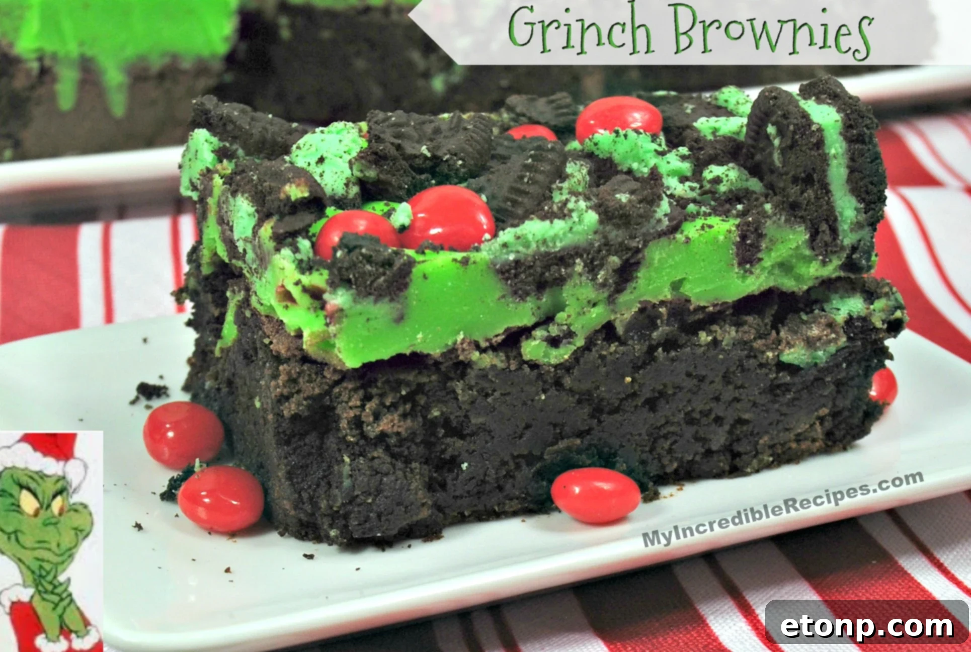 Close-up of vibrant green Grinch brownies topped with red candies and chopped Oreos, ready to be enjoyed.