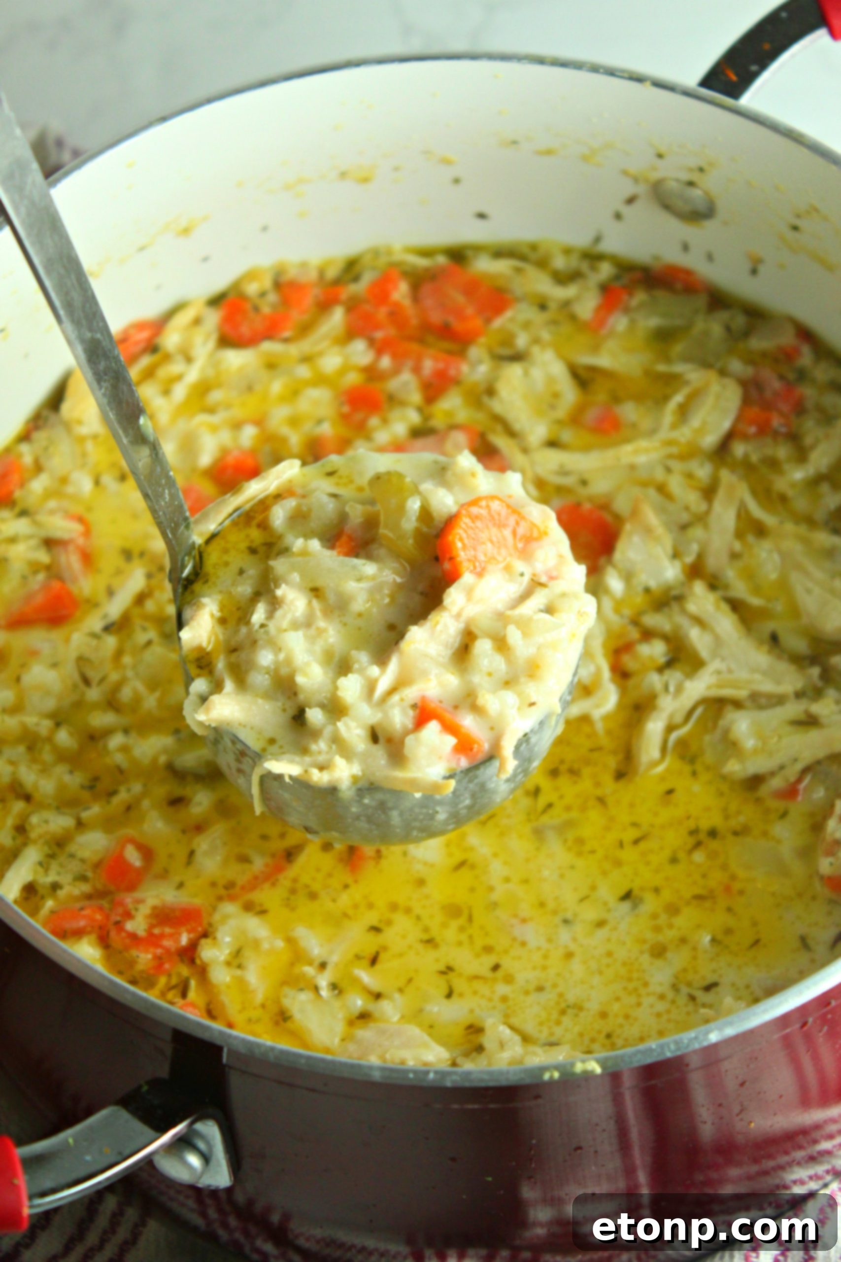 Easy Chicken and Rice Soup 6 Chicken and rice soup being stirred in a large pot on the stove, steam rising.