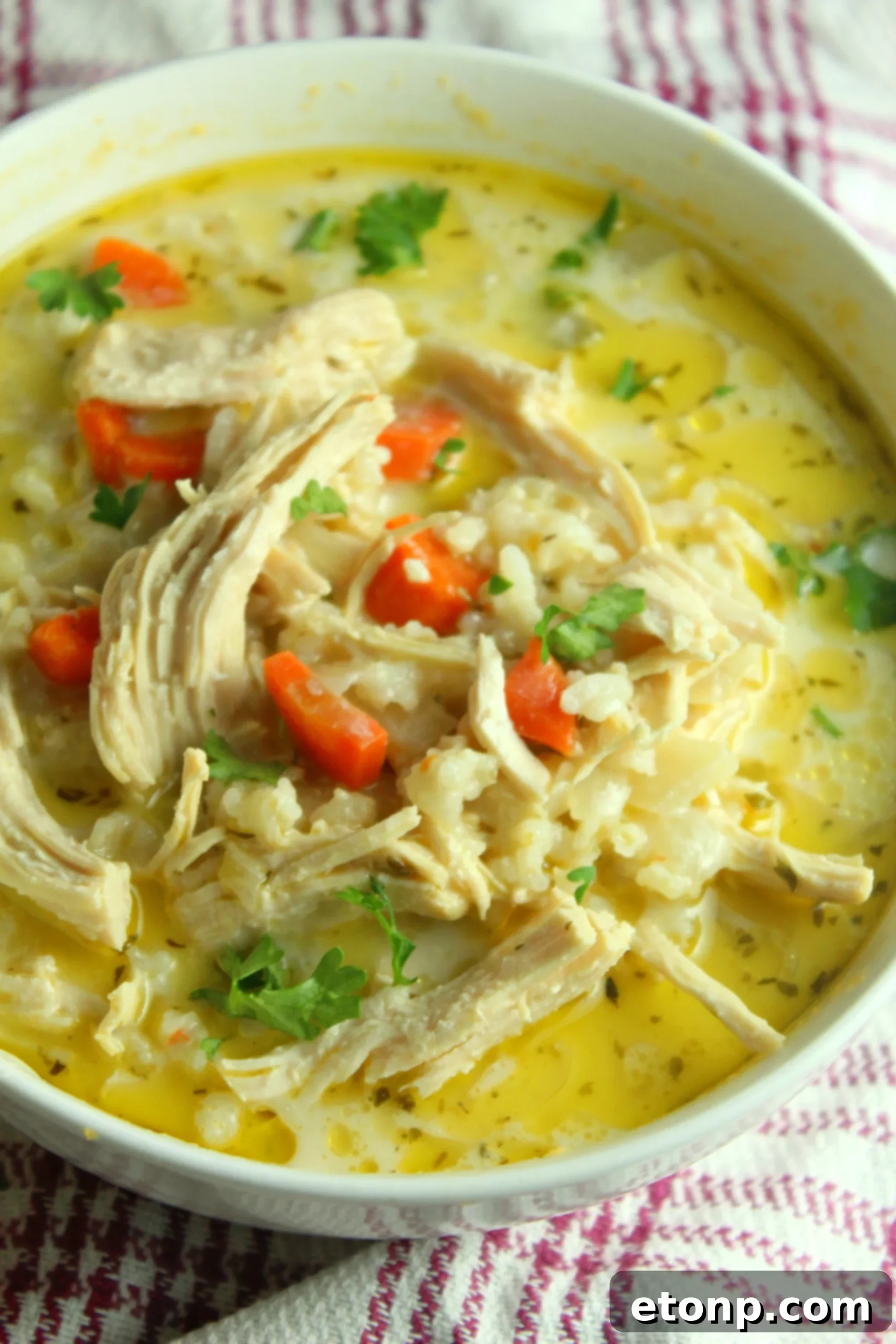 Easy Chicken and Rice Soup 7 A ladle scooping creamy chicken and rice soup from a pot, showing generous portions.