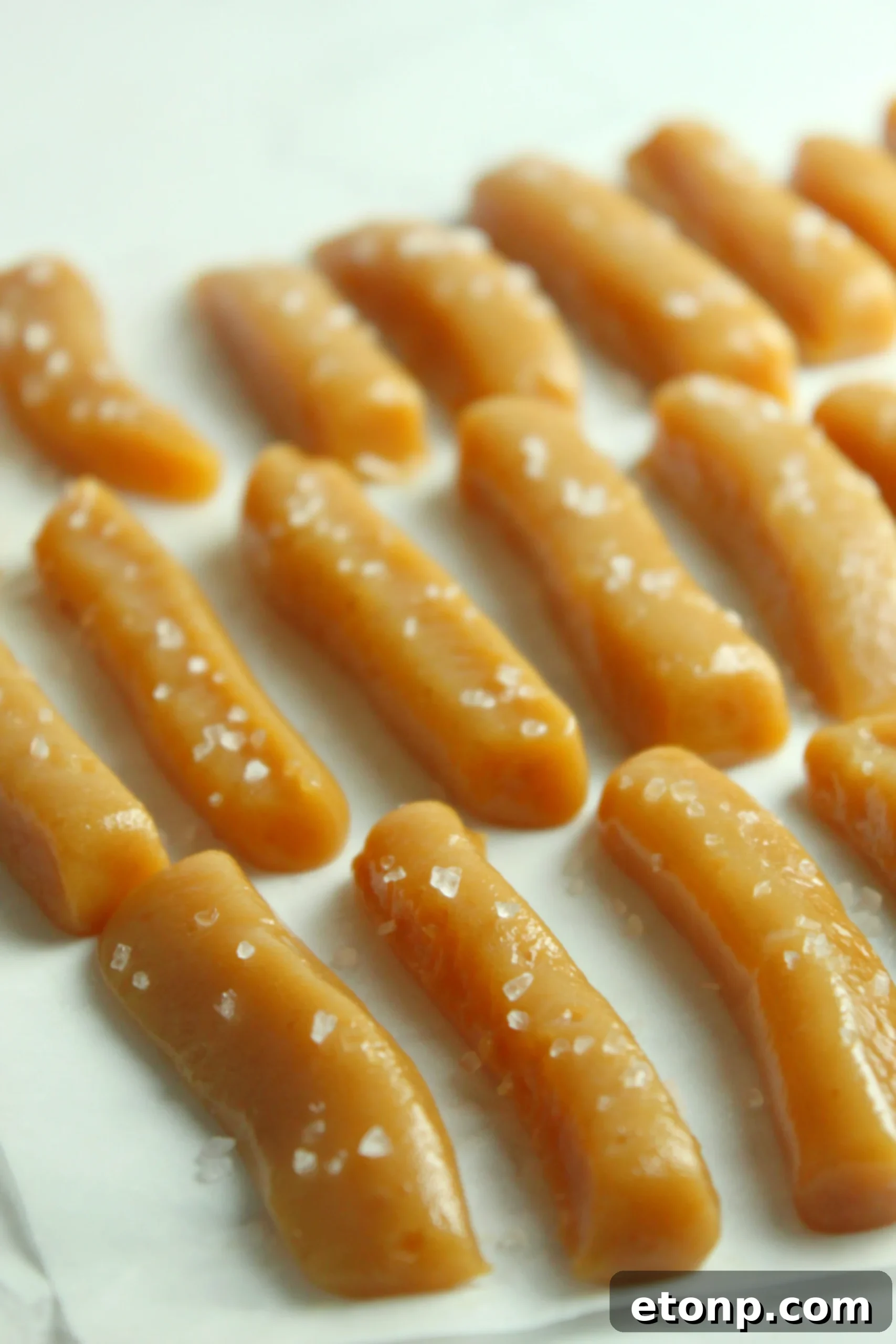 Close-up of a stack of unwrapped homemade caramels, showing their soft, light brown interior and smooth exterior.