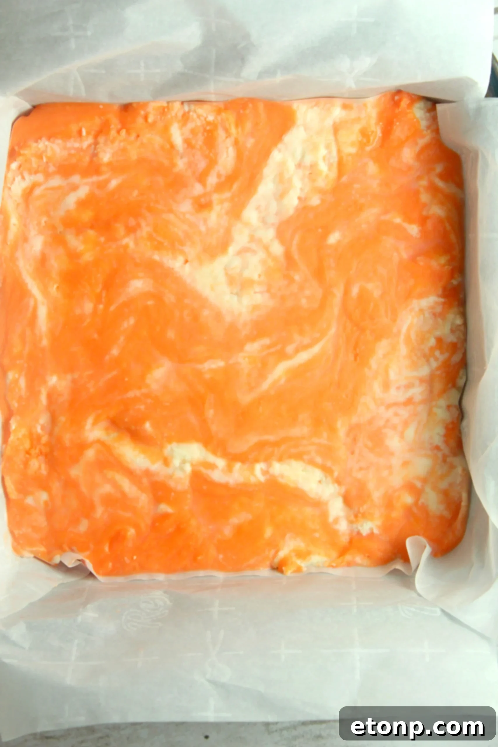 Easy No Bake Orange Creamsicle Fudge 3 A close-up of a large piece of orange creamsicle fudge, showcasing its smooth, swirled texture.