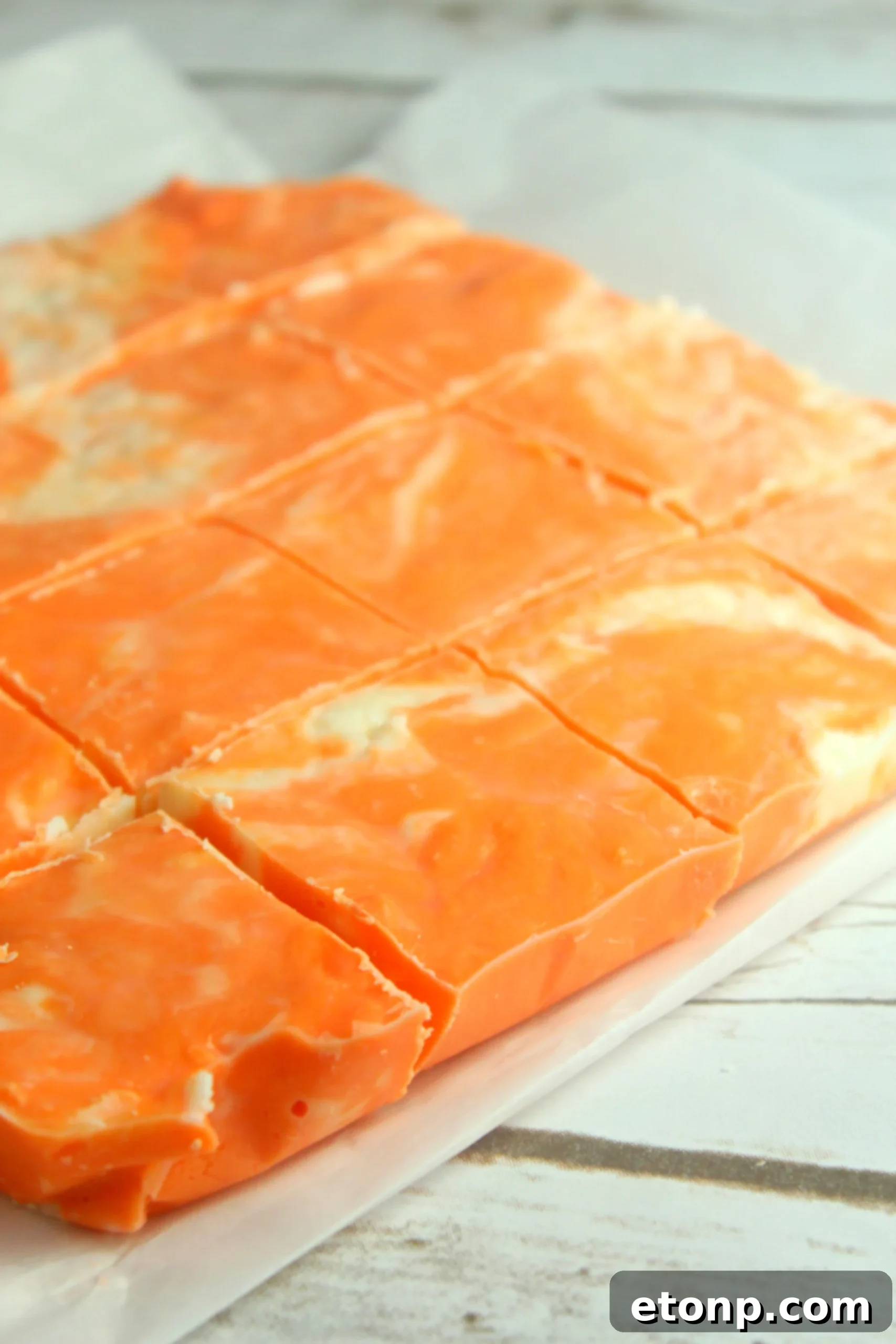 Easy No Bake Orange Creamsicle Fudge 4 Several pieces of homemade orange creamsicle fudge artfully arranged, highlighting the vivid orange hue.