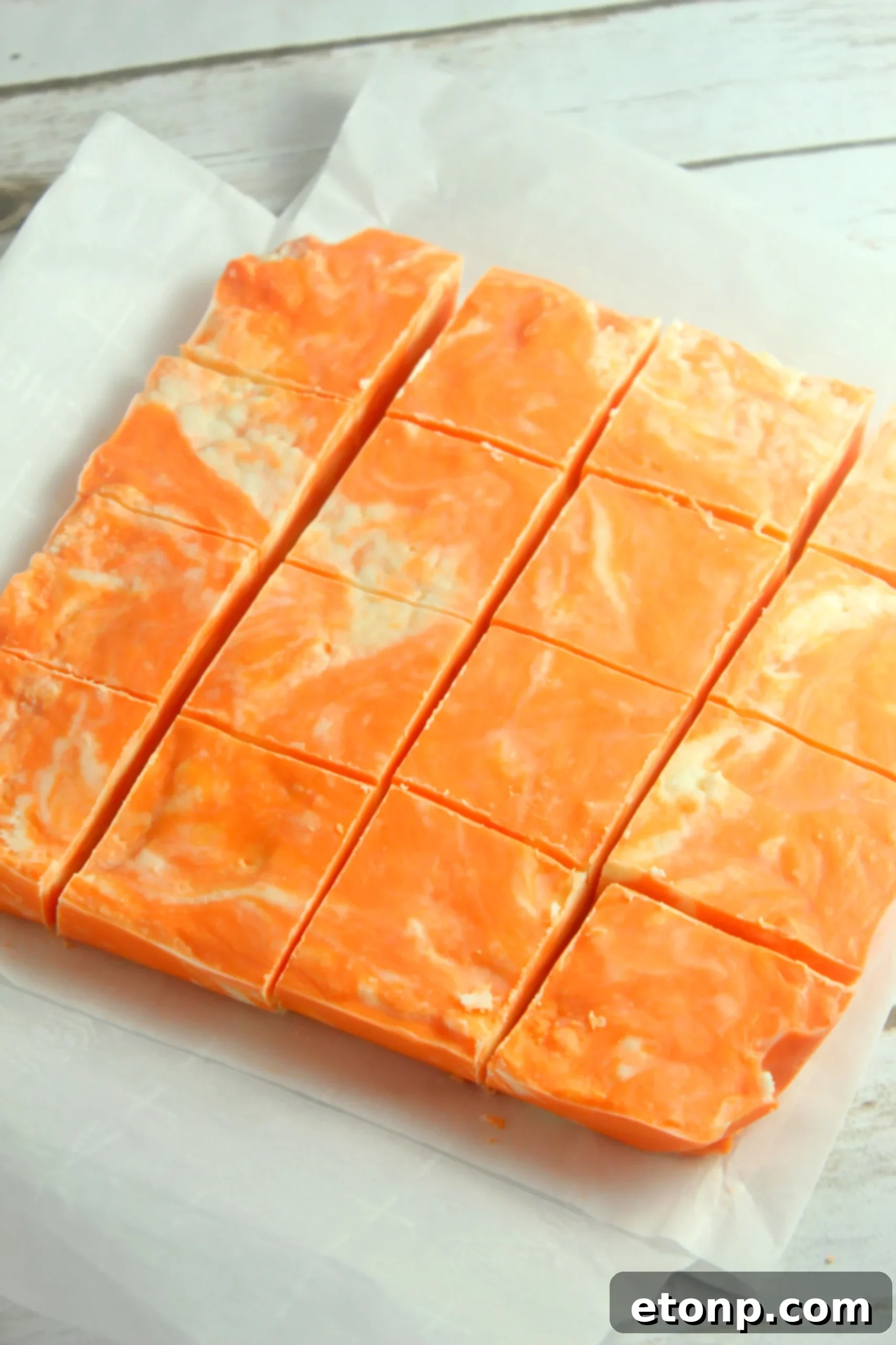 Easy No Bake Orange Creamsicle Fudge 5 A hand reaching for a piece of orange creamsicle fudge, suggesting its irresistible appeal.