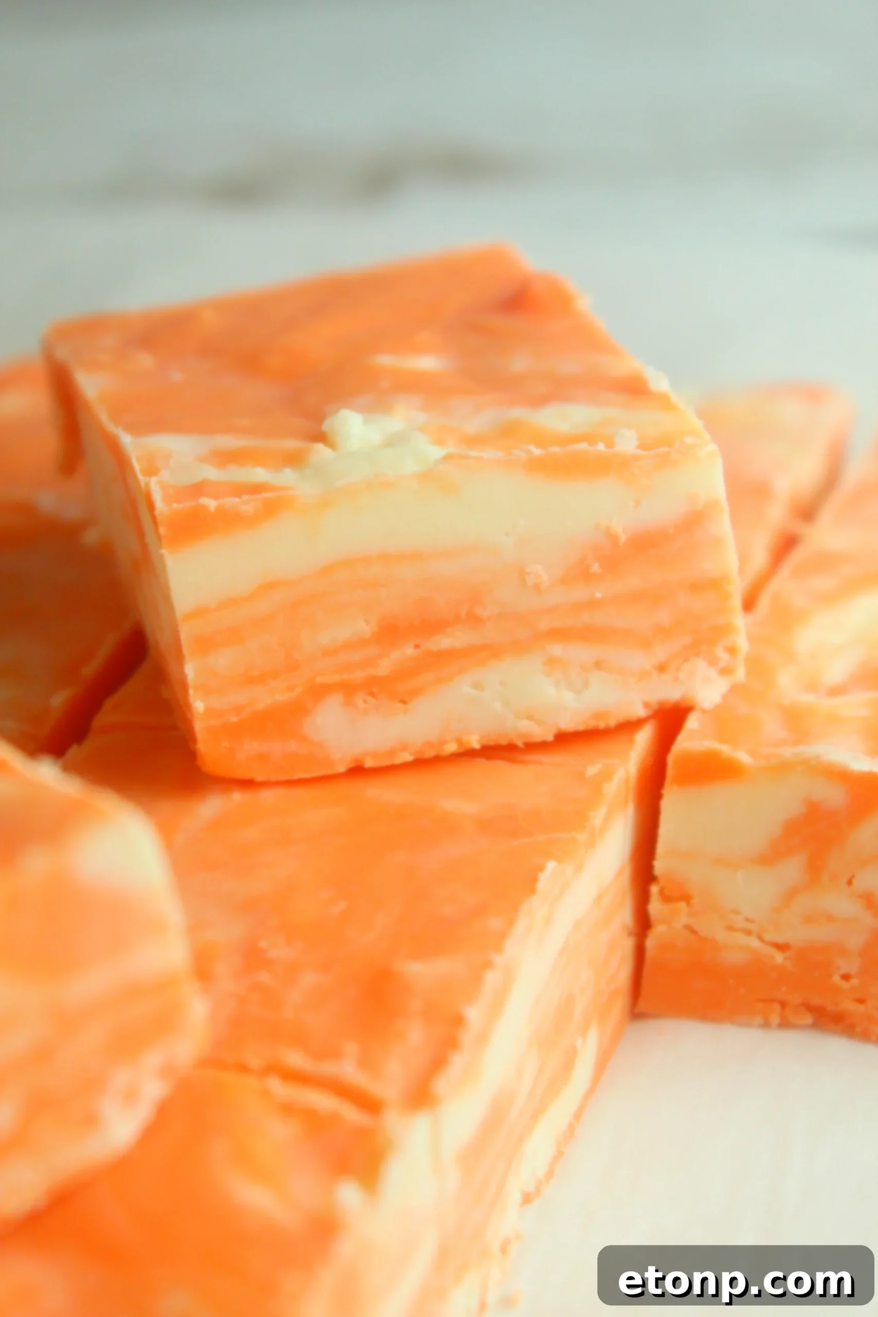 Easy No Bake Orange Creamsicle Fudge 8 A top-down view of the orange creamsicle fudge in a pan, with a knife poised to cut it into squares.