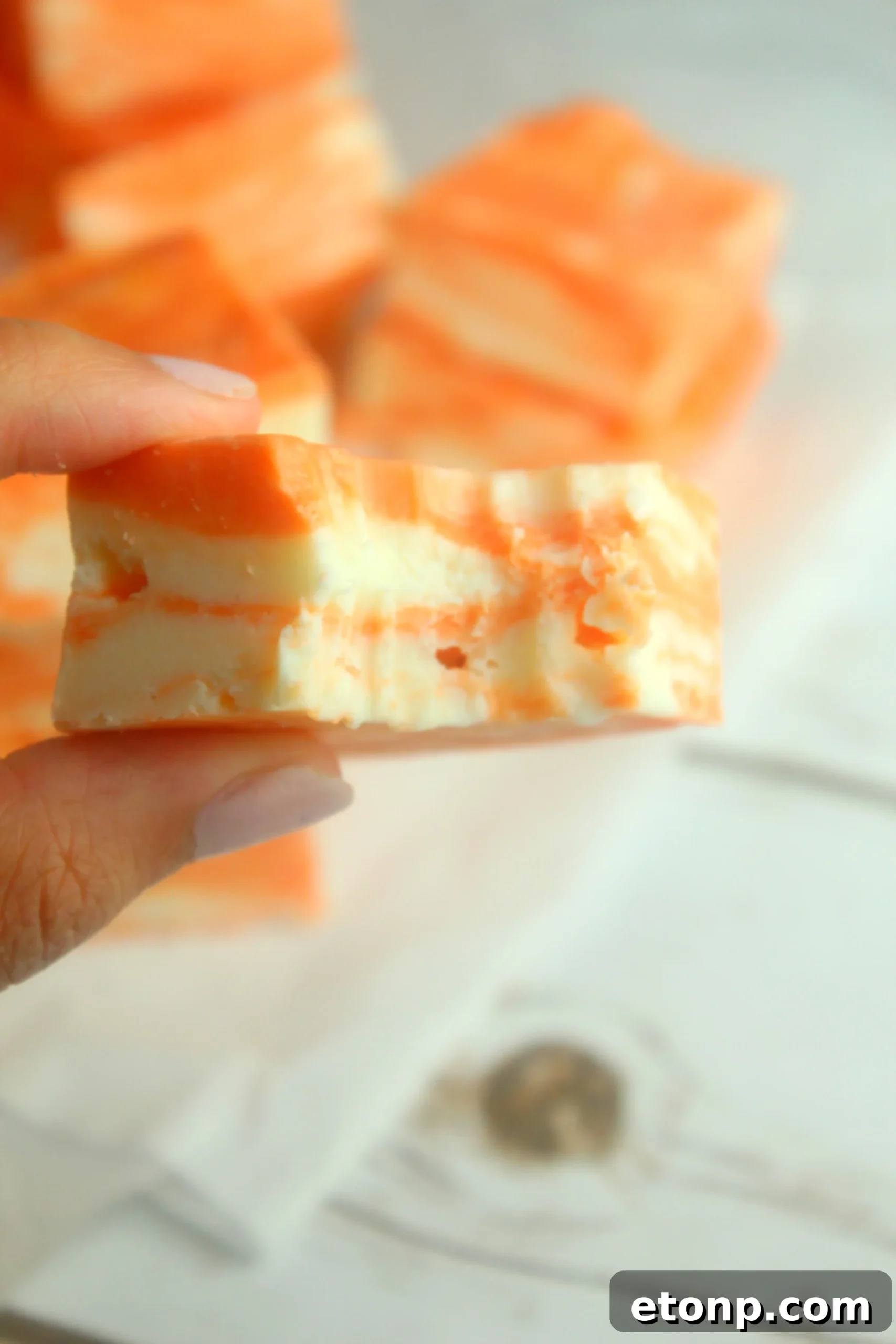 Easy No Bake Orange Creamsicle Fudge 9 A close-up of a single perfect square of orange creamsicle fudge, highlighting the swirl.