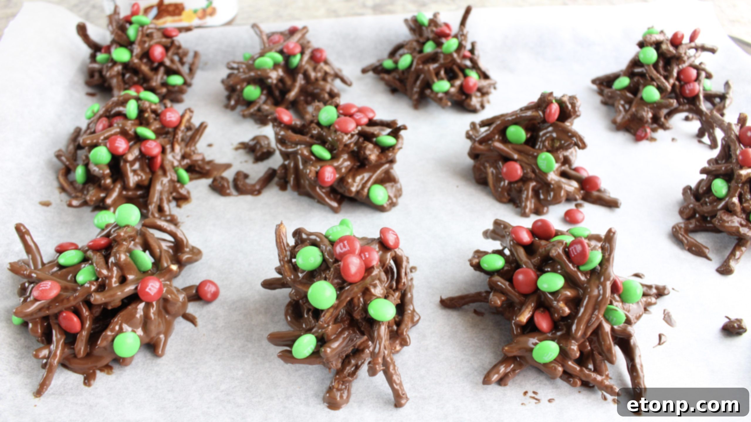 Finished chocolate haystacks cooling on a baking sheet, topped with colorful M&M's.