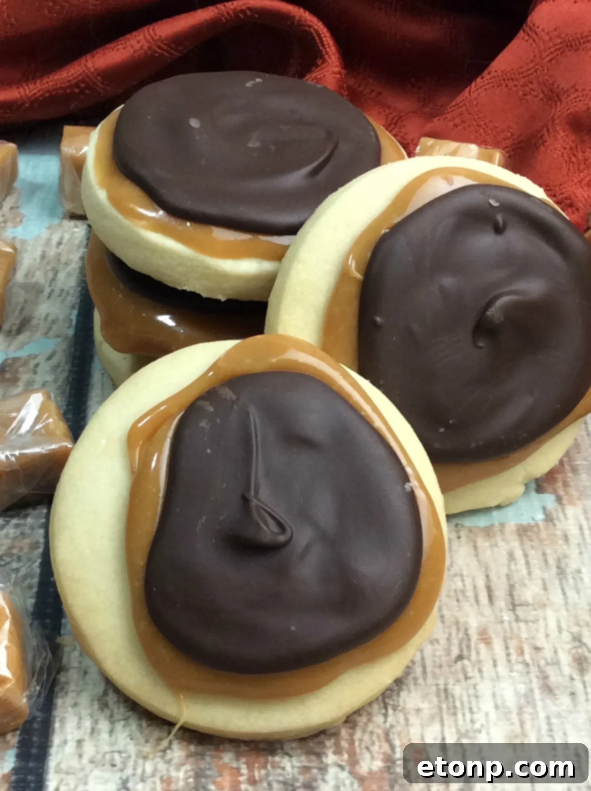 Copycat Twix Cookies 7 A hand reaching for a delicious homemade Twix cookie, inviting a bite of the layered dessert.