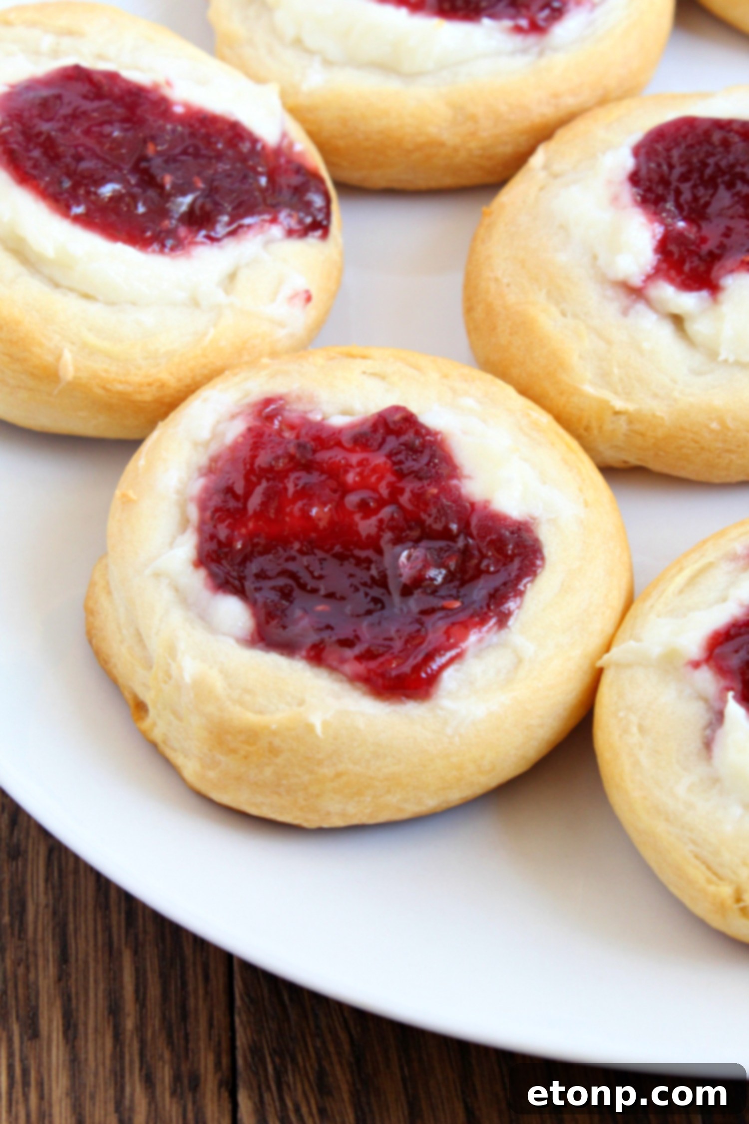 Luscious Raspberry Cream Cheese Crescents 4 Side view of a baked Raspberry Cream Cheese Crescent Danish with a clear focus on the flaky pastry and vibrant raspberry jam peaking through the cream cheese.