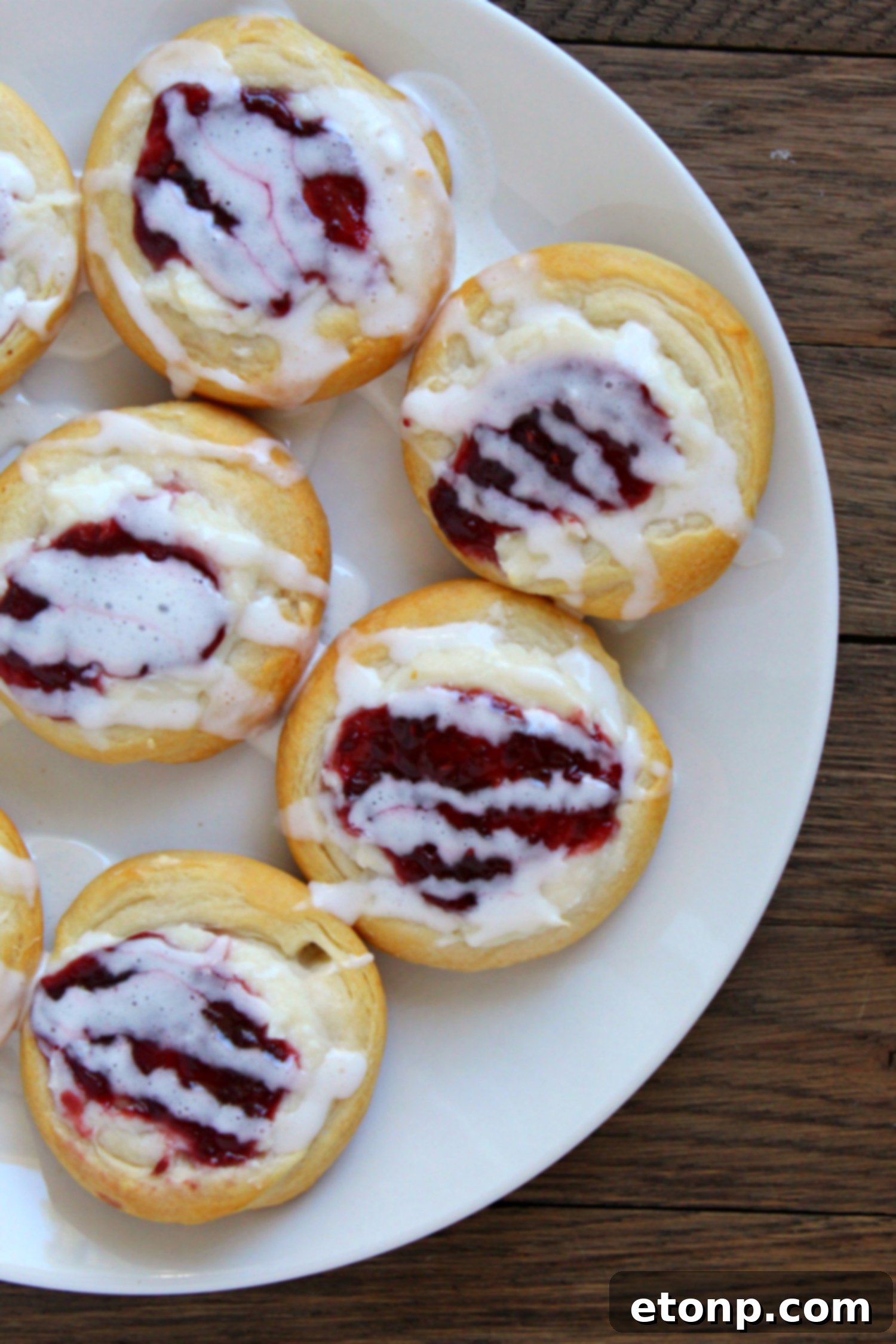 Luscious Raspberry Cream Cheese Crescents 7 A Raspberry Cream Cheese Crescent Danish being lifted from a baking sheet, highlighting its warm, soft texture.