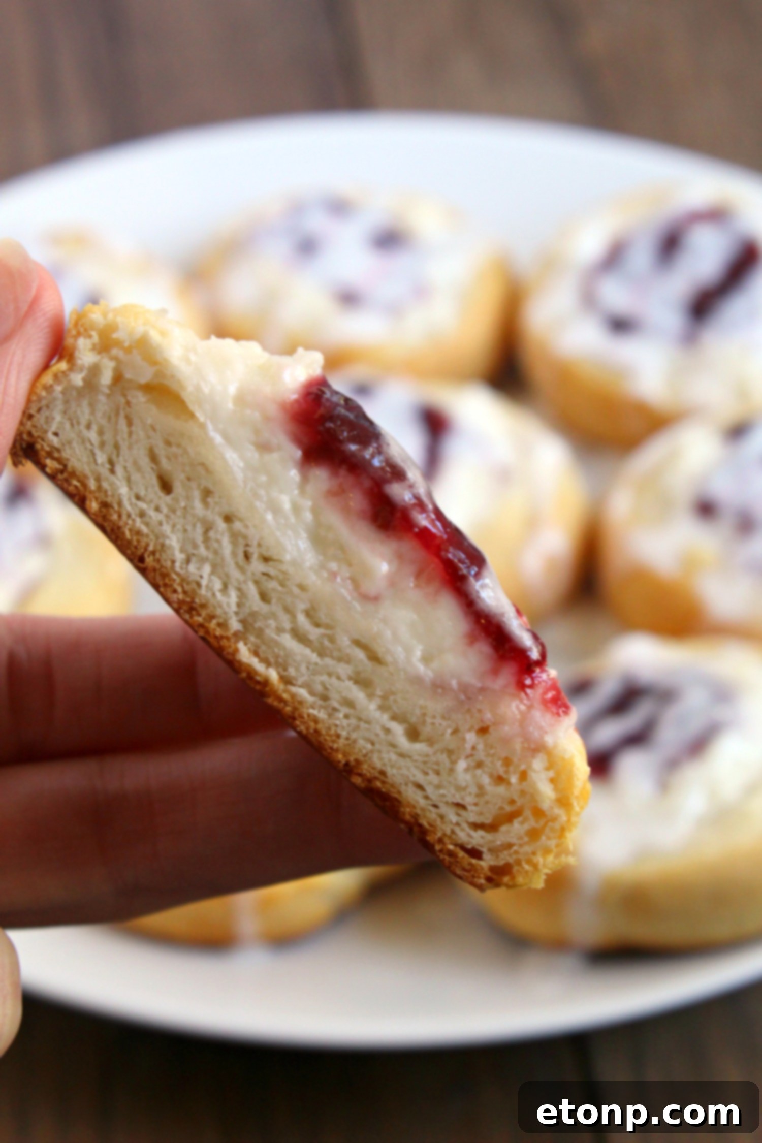Luscious Raspberry Cream Cheese Crescents 9 A close-up of a single Raspberry Cream Cheese Crescent Danish with a clear focus on the flaky layers of the pastry.