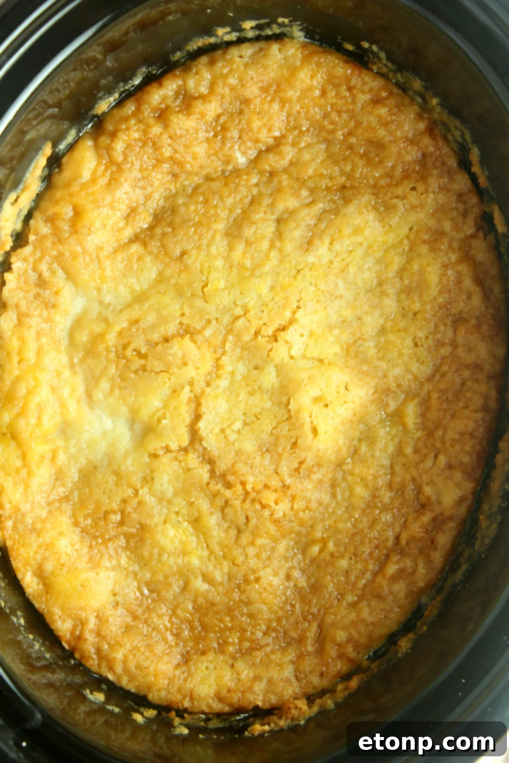 A scoop of rich vanilla ice cream melting decadently over a warm serving of peach cobbler