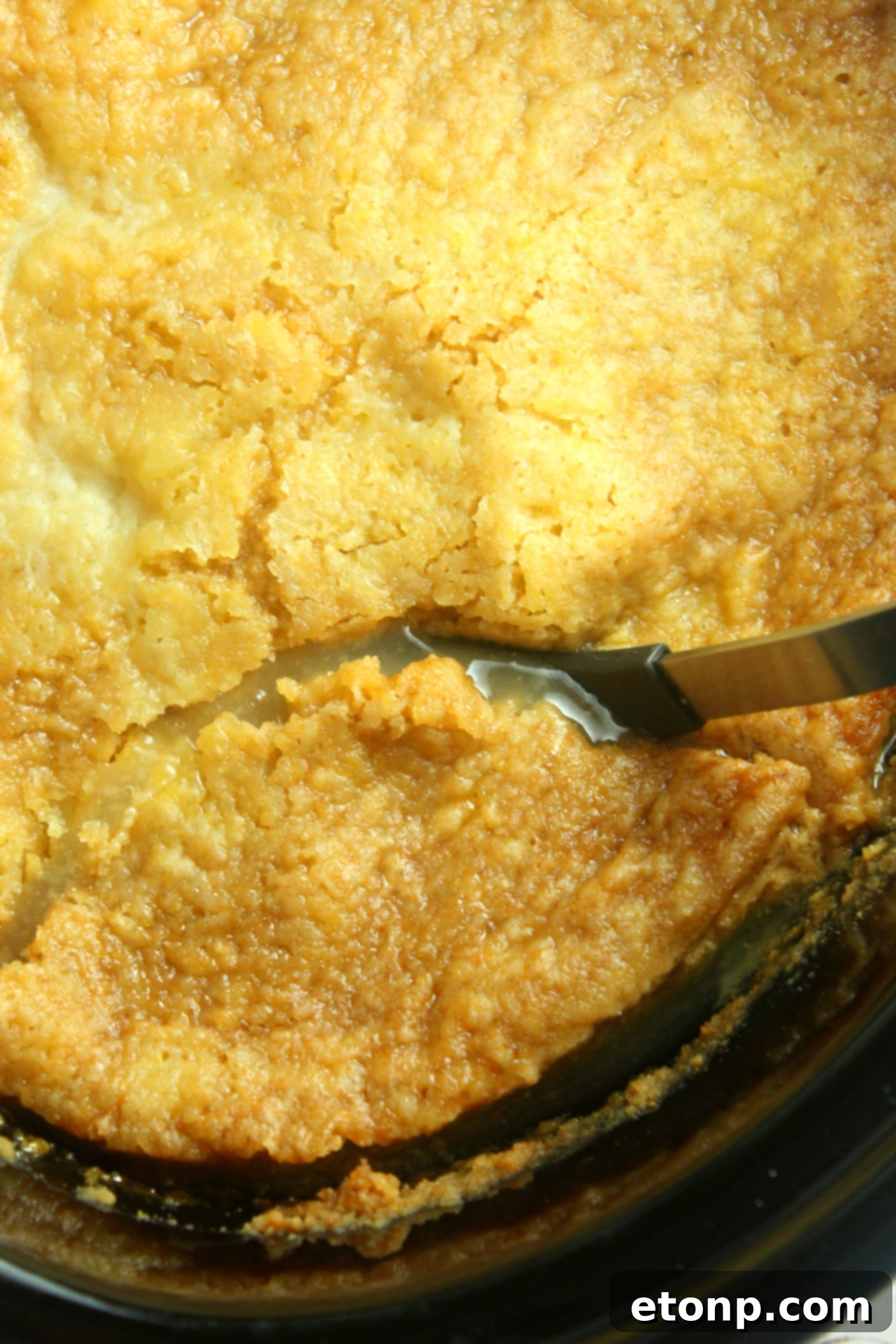 Top-down close-up of peach cobbler simmering in a slow cooker, edges golden and bubbly