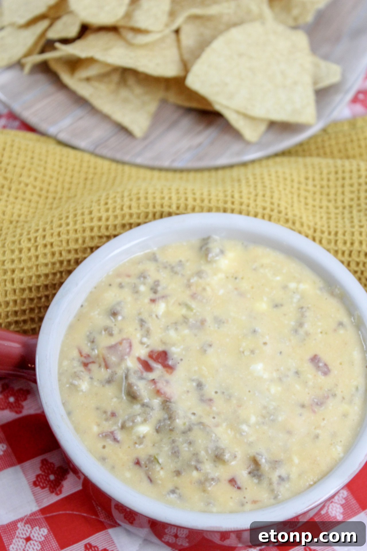 A close-up of a chip generously loaded with the warm, creamy cheesy sausage dip, showcasing its rich texture.