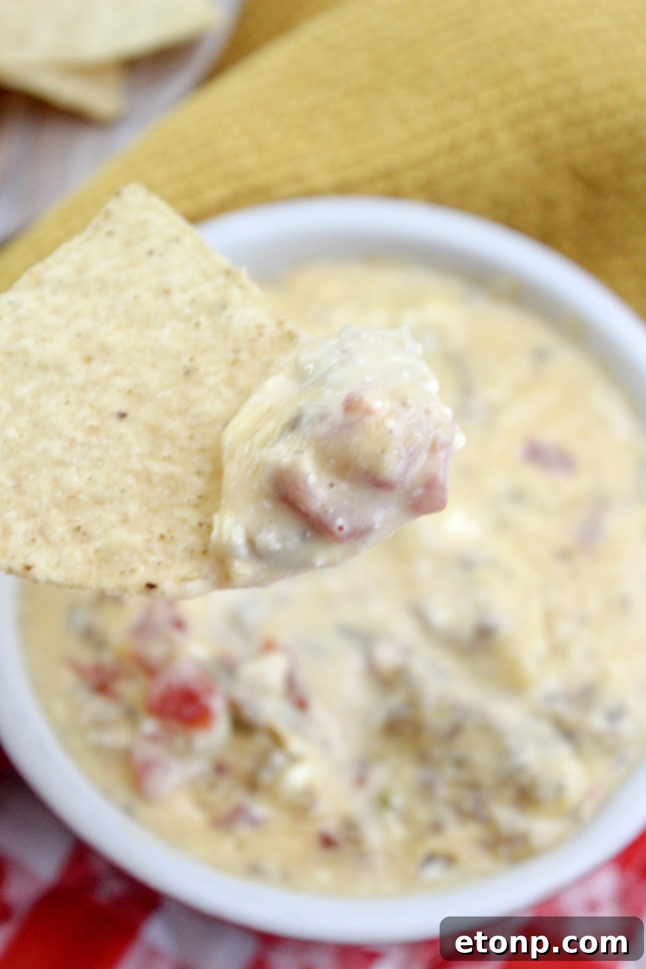 An overhead shot of the completed cheesy sausage dip in a serving bowl, garnished with a sprinkle of fresh herbs, surrounded by a variety of dippers.