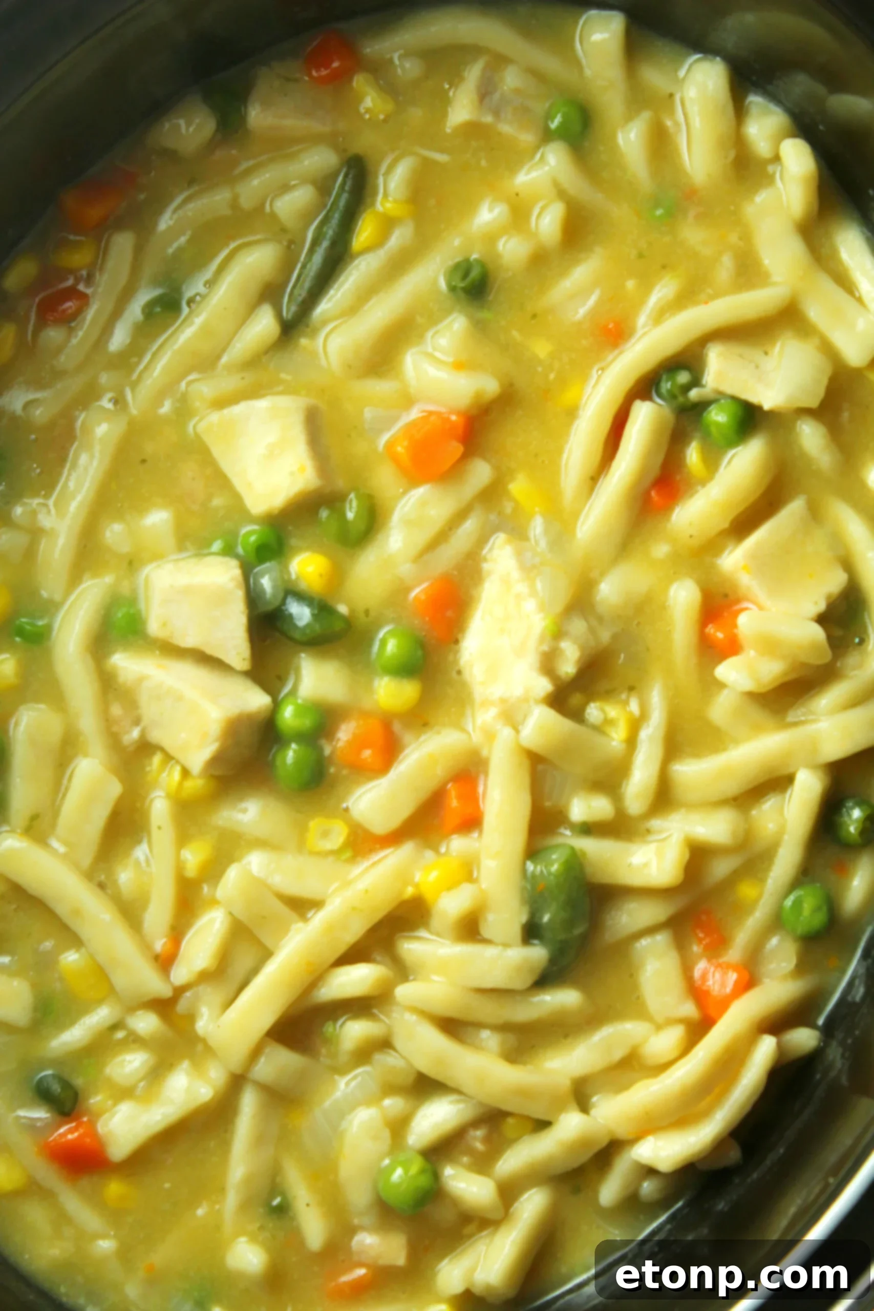 A close-up shot of fresh, chopped parsley, often used as a garnish for chicken noodle soup.