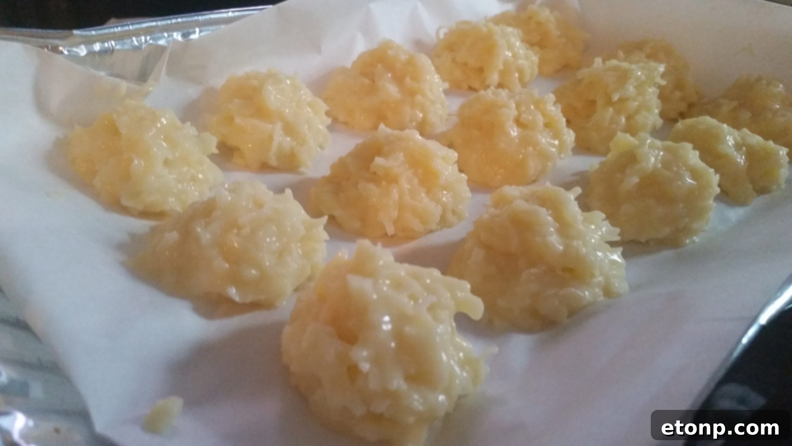 A large batch of coconut snowballs on a baking sheet, showcasing their perfect shape