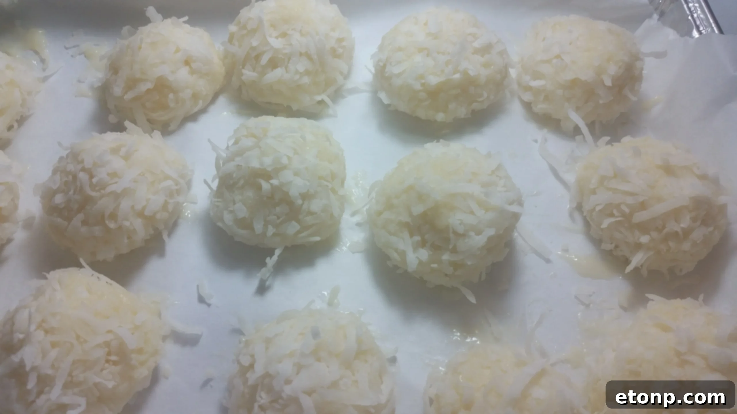 Several coconut snowballs stacked invitingly on a white plate