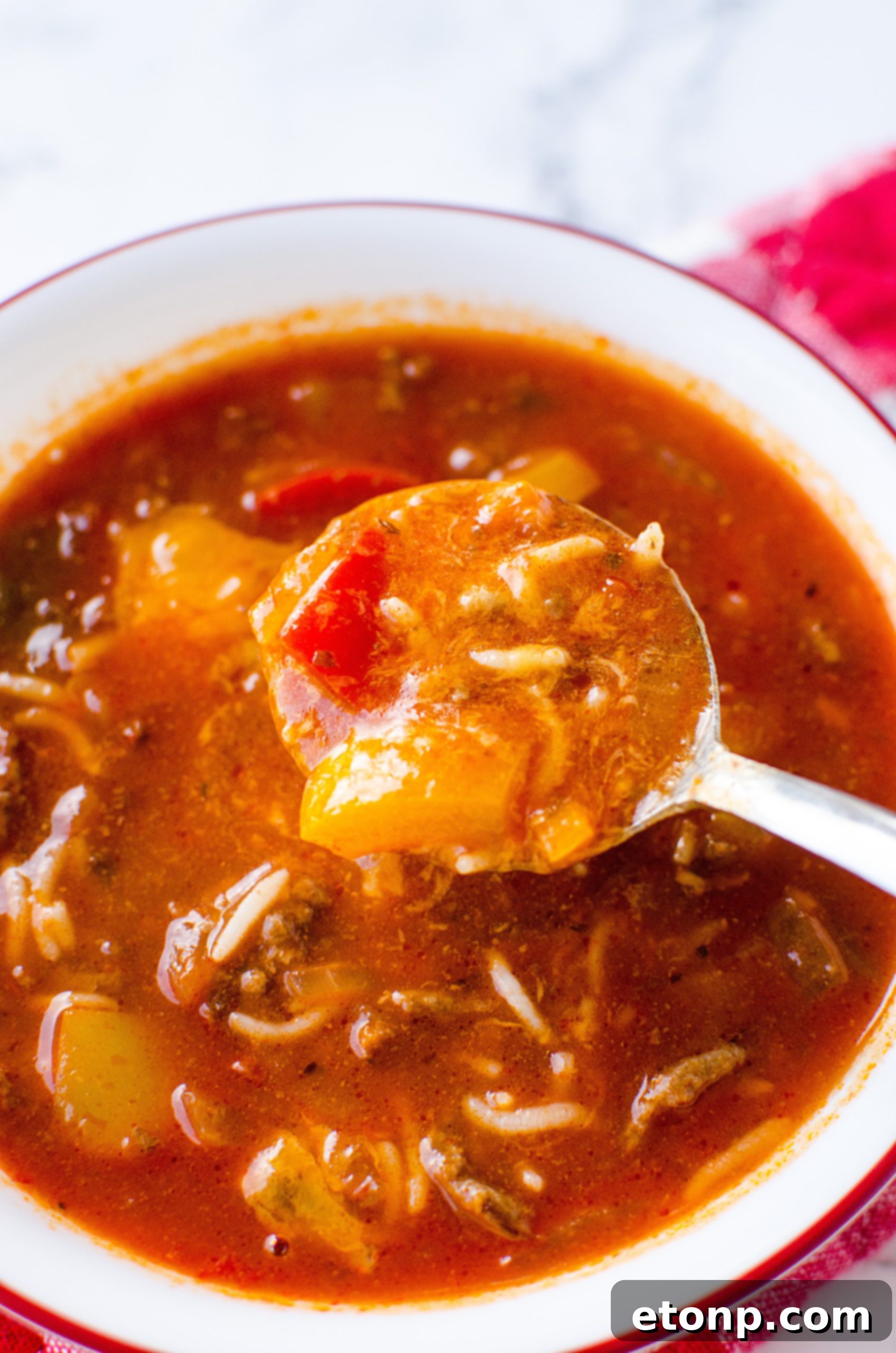 Close-up shot of a bowl of Stuffed Pepper Soup, showing ground beef, rice, and colorful bell peppers in a rich tomato broth.