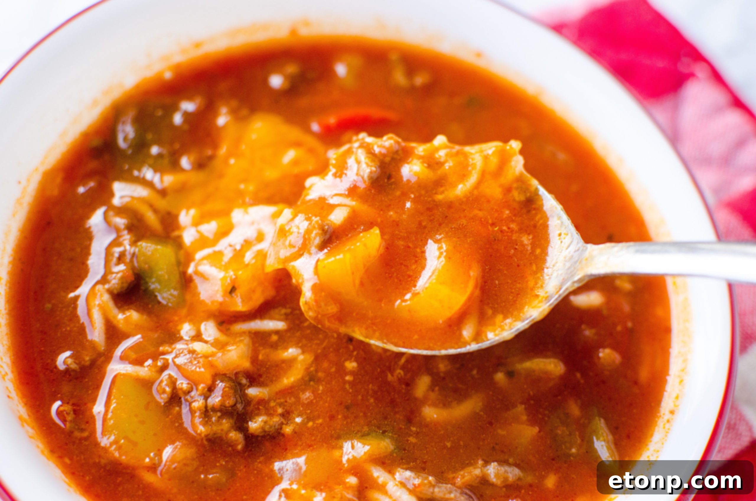 A close-up of a spoon scooping out Stuffed Pepper Soup from a bowl, showing the texture and ingredients.