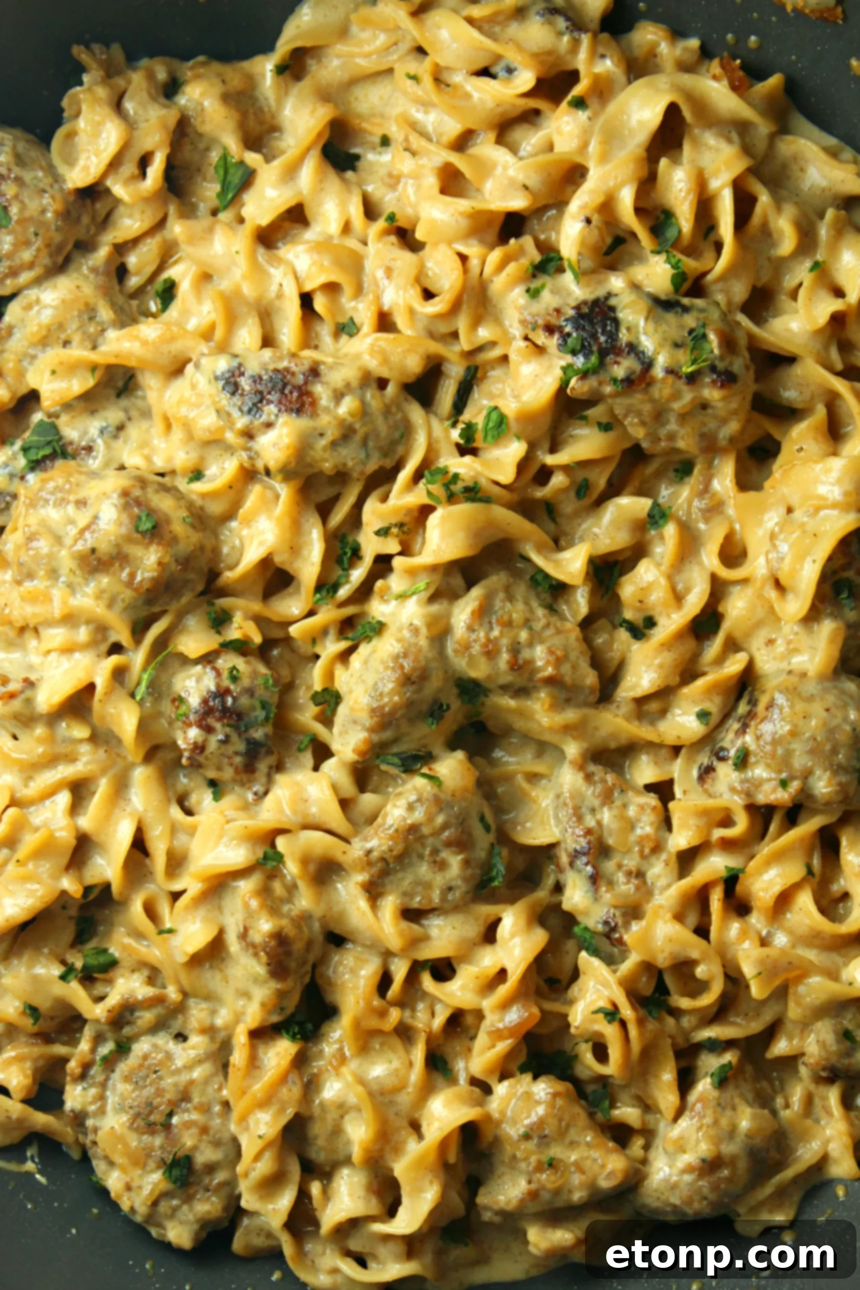 A generous serving of Creamy French Onion Sausage Pasta garnished with fresh herbs