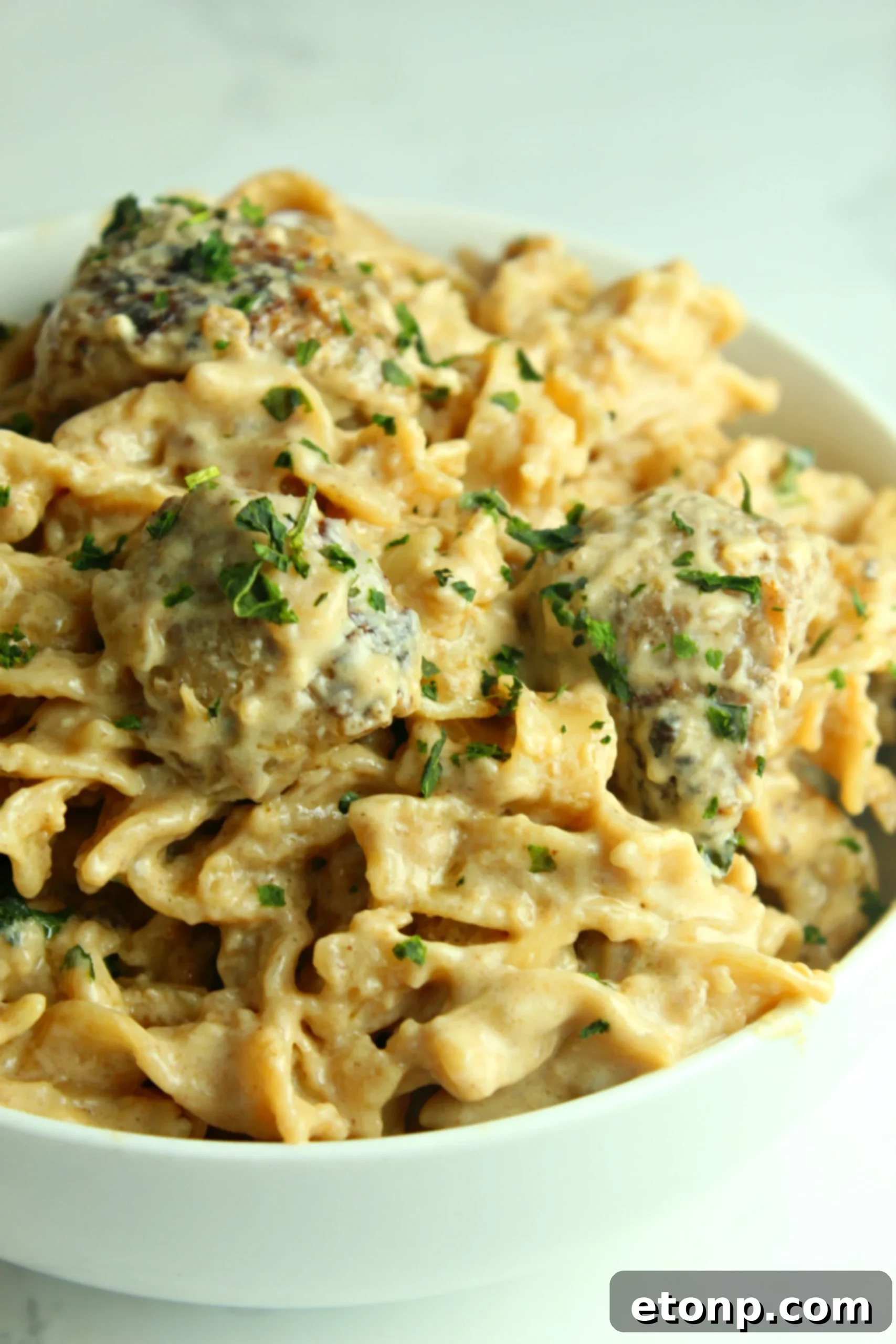 Plate of Creamy French Onion Sausage Pasta served with a side of crusty garlic bread