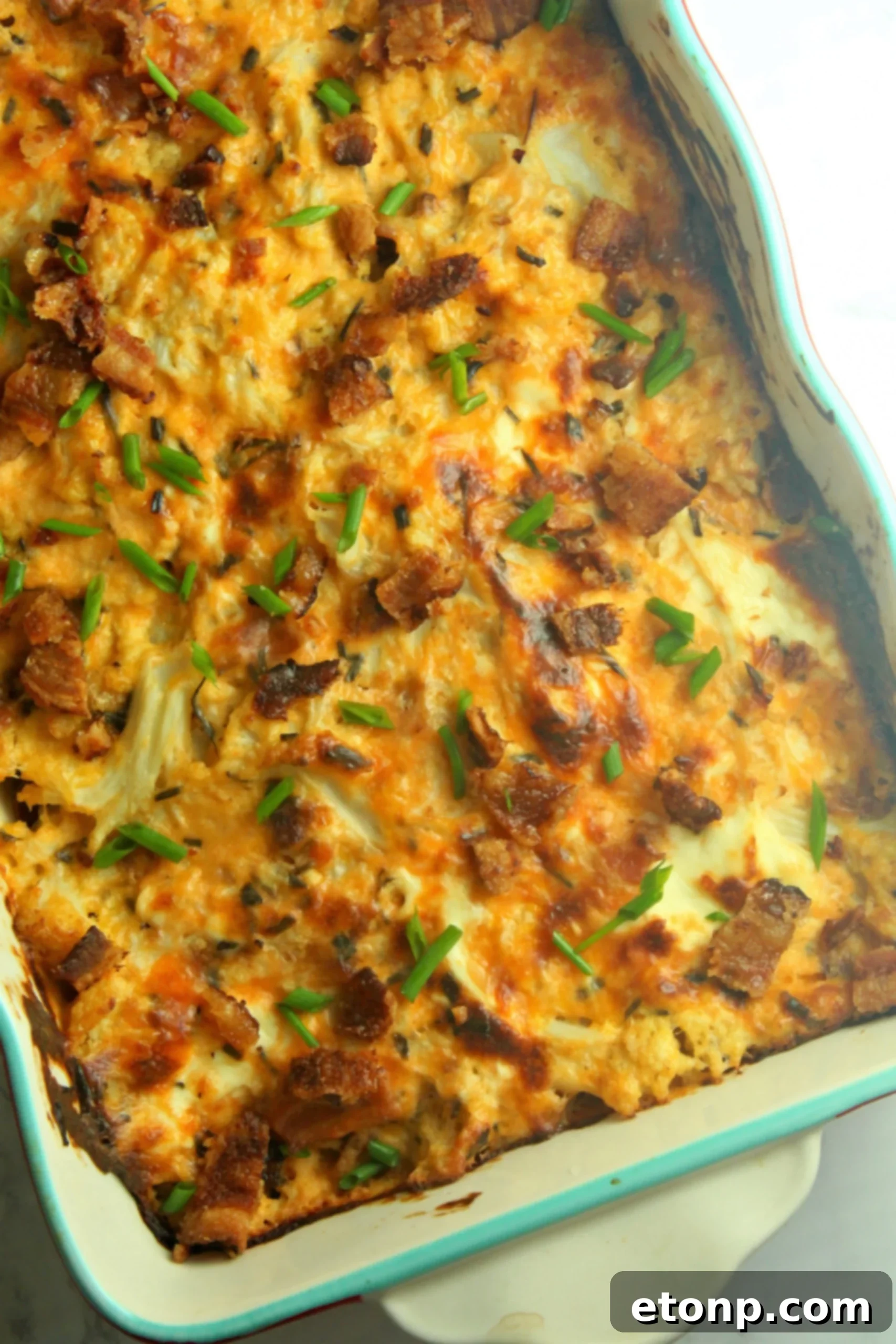 Close-up of the Loaded Cheesy Cauliflower Casserole, showing golden-brown melted cheese and crispy bacon bits.