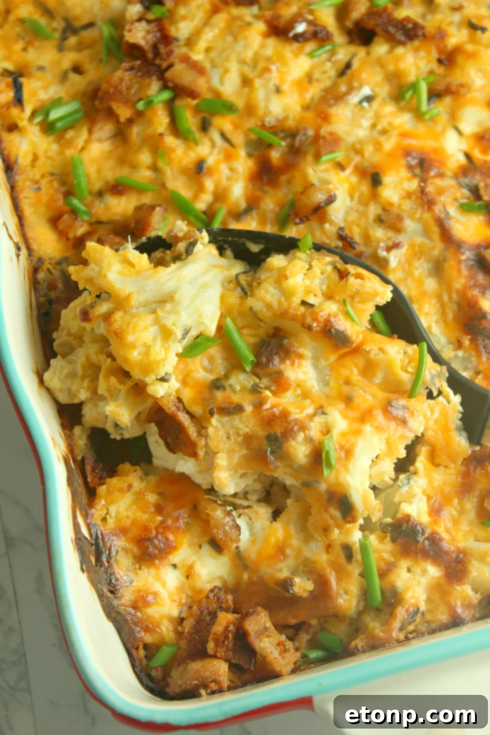 A large baking dish filled with the golden-brown Loaded Cheesy Cauliflower Casserole, straight from the oven.